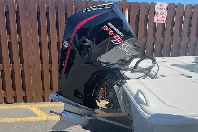 Outboard motor on a 2026 Mako 18 Pro Skiff boat, parked near a wooden fence.