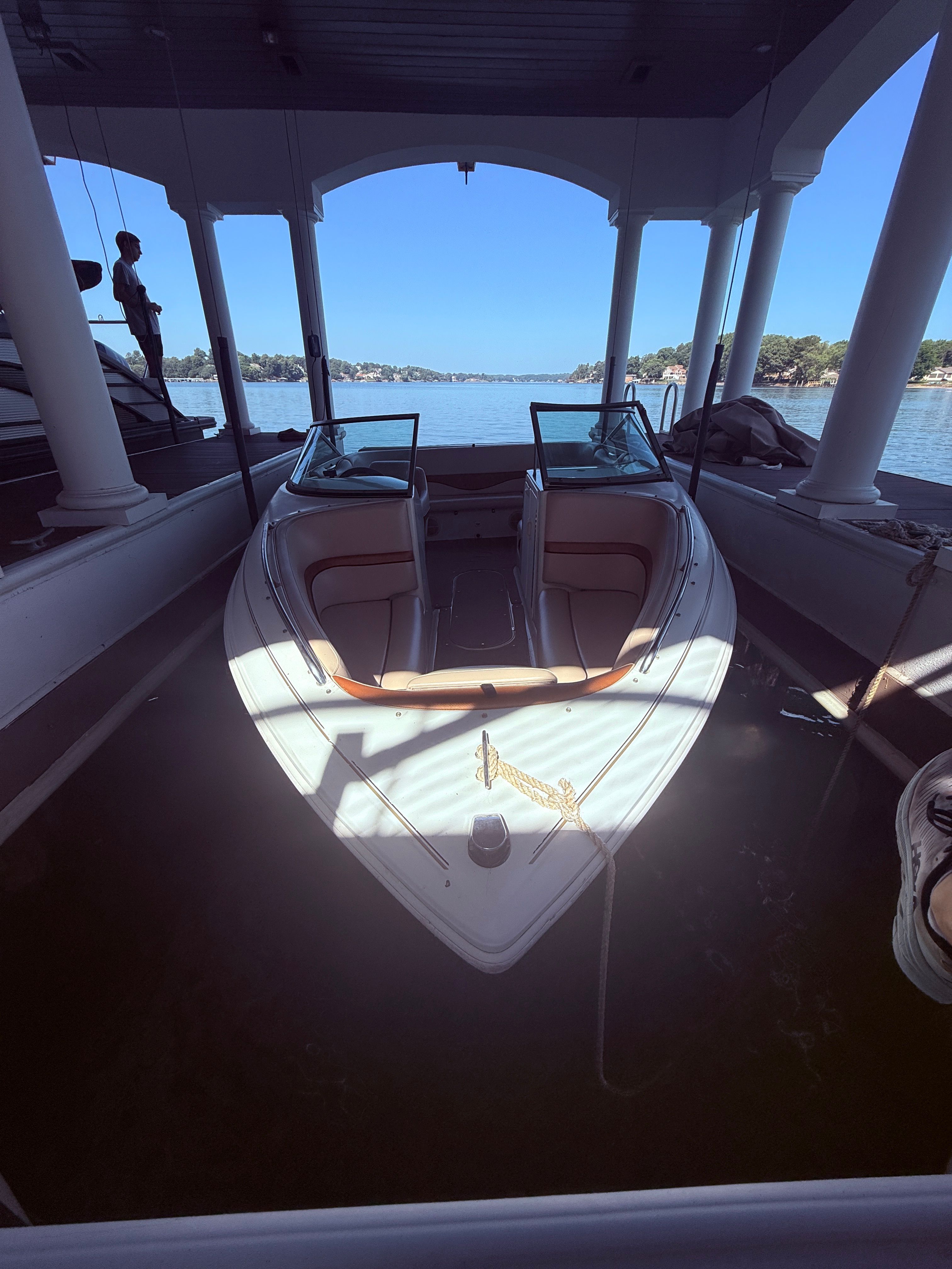 A 2000 Starcraft Next Star 19 boat is docked under a covered area, overlooking the water.