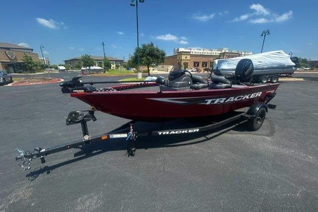 2026 Tracker Super Guide V-16 SC boat on trailer in parking lot under clear sky.