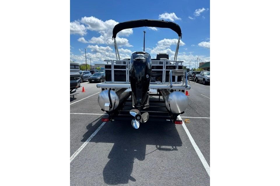 2026 Sun Tracker Fishin' Barge 20 DLX pontoon boat with outboard motor in parking lot.