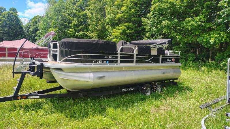 A 2019 White River pontoon boat on a trailer in a grassy area.