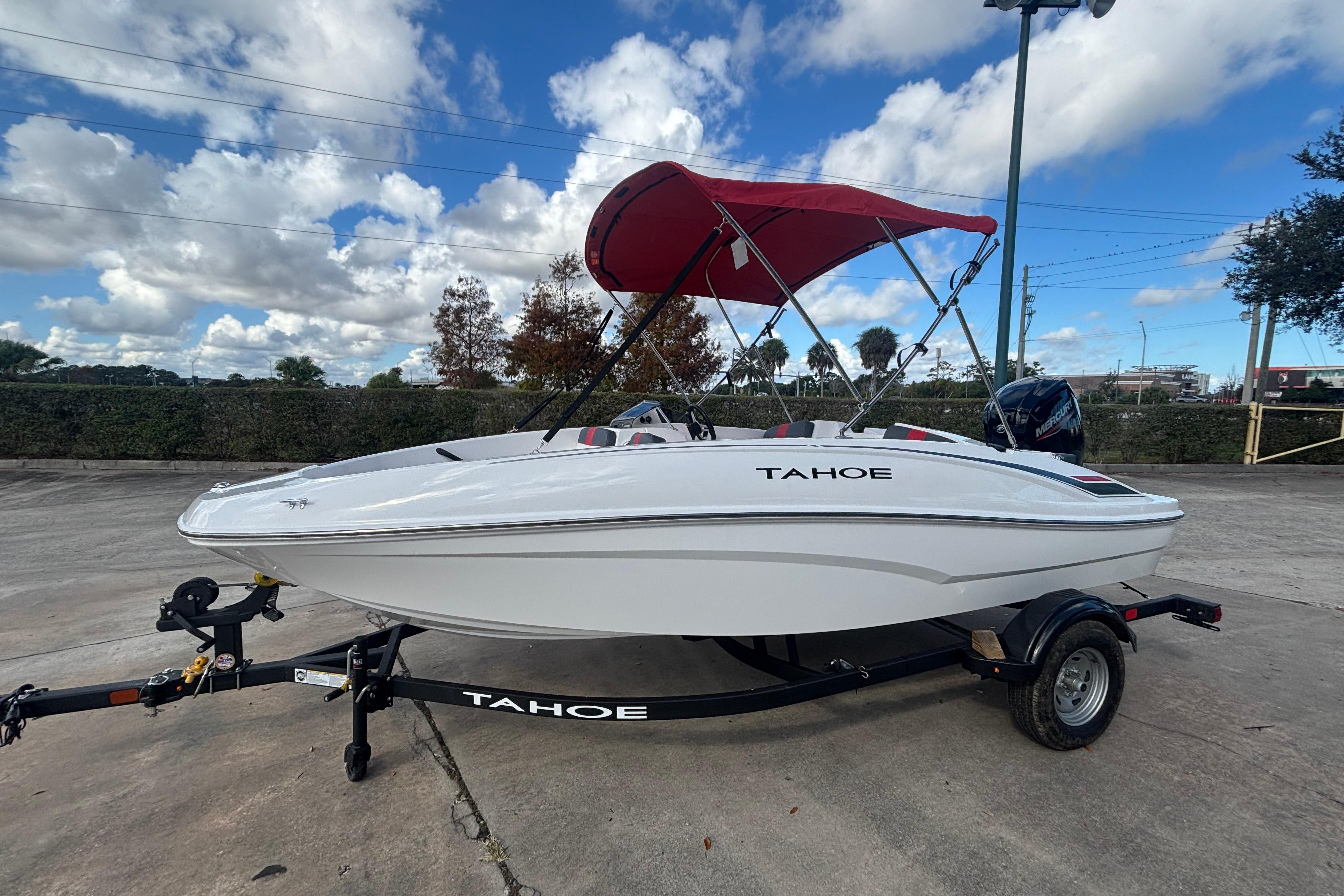 2026 Tahoe T16 boat with red canopy on trailer under blue sky.