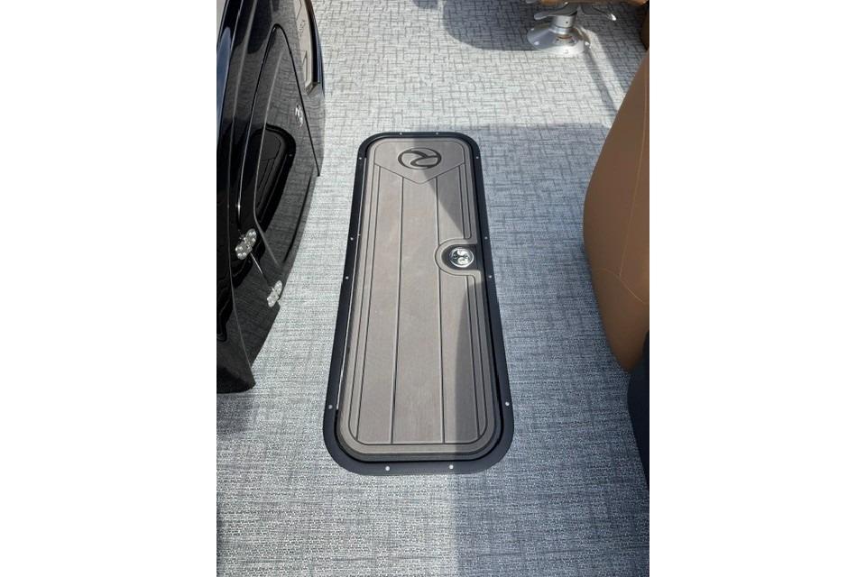 2026 Regency 230 DL boat floor with storage hatch on textured carpet.