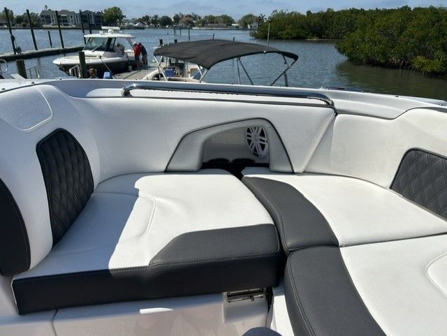 A modern boat with white and black seating, water and trees in the background.