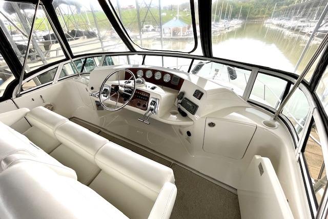 Interior helm of 2002 Silverton 43 Motor Yacht with white seating and control panel.