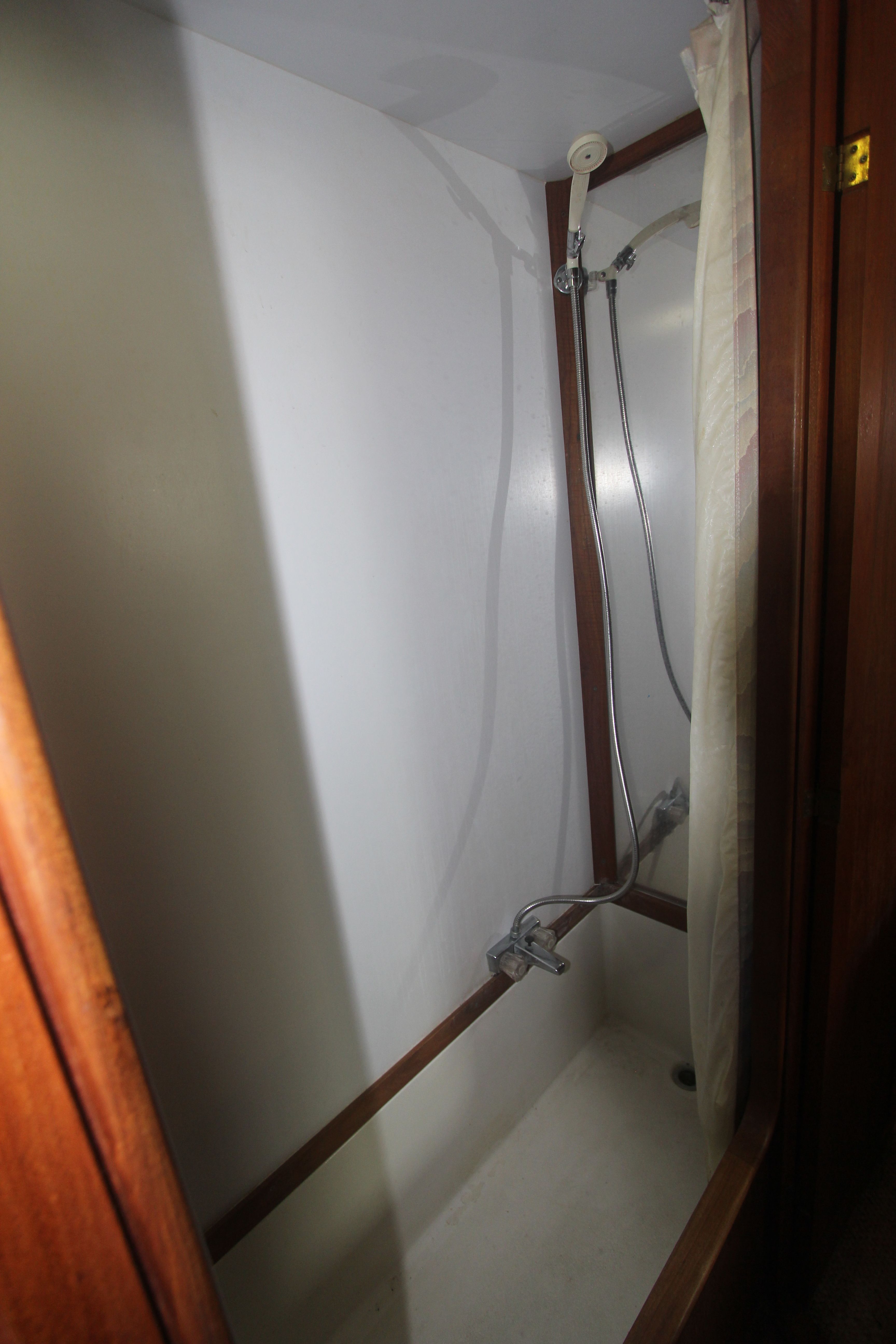A simple shower stall with a showerhead and curtain inside a boat.