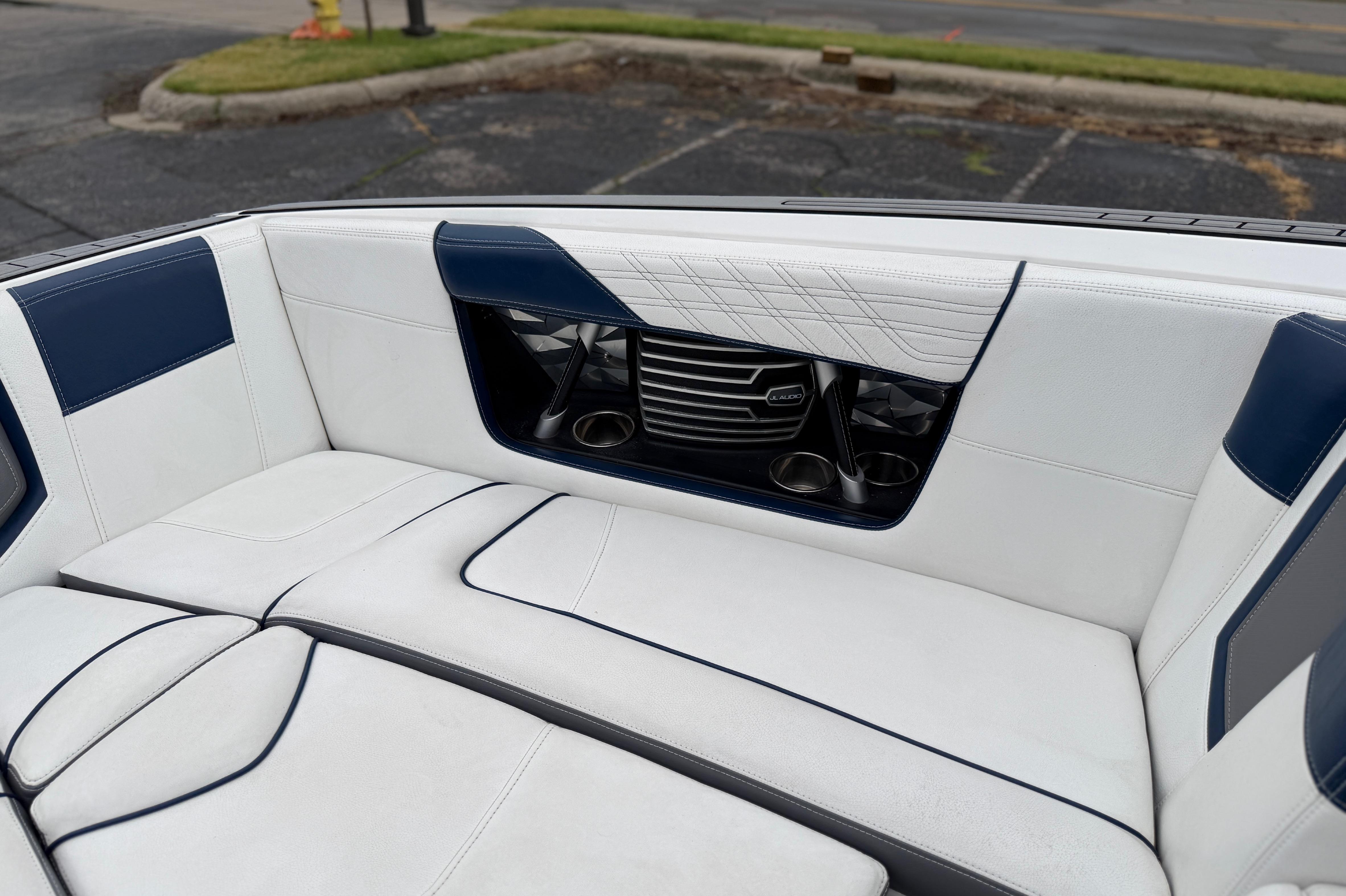 2016 Naitique G25 boat interior with white and blue seating, cup holders, and speaker system.