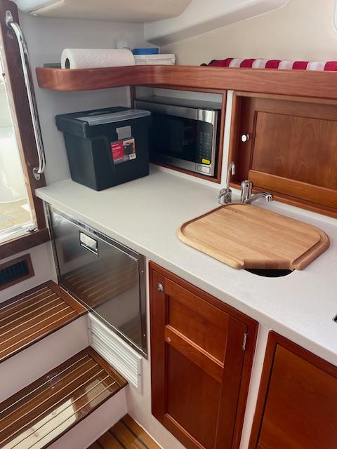 2023 MJM 35z yacht kitchen with wooden cabinets, microwave, and cutting board.