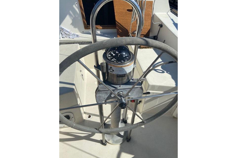 Steering wheel and compass of a 1977 C&C 29 sailboat cockpit.