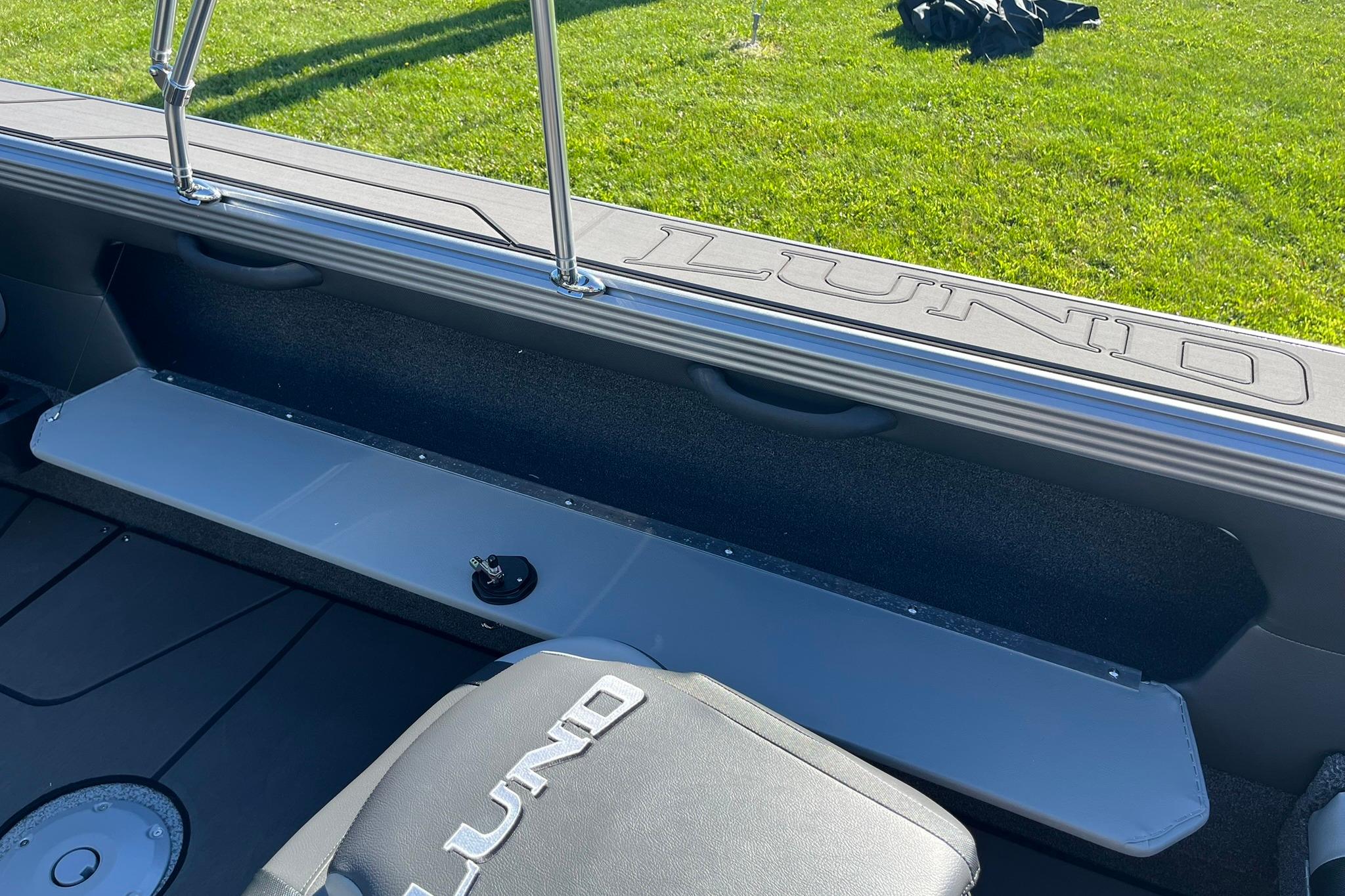2026 Lund 2275 Baron boat interior with branded seating and storage, on grassy background.