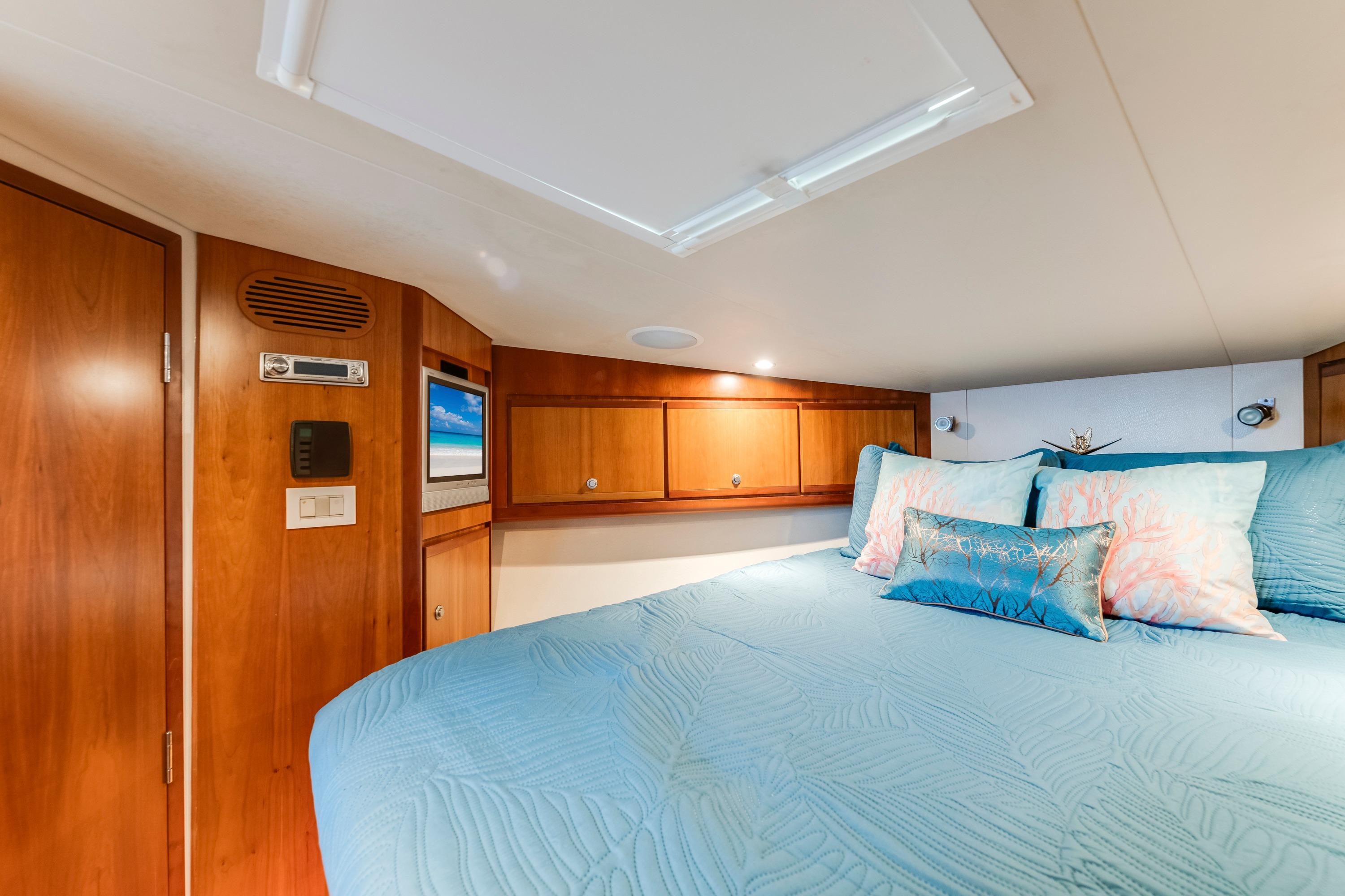 Luxurious cabin interior of 2004 Bertram 390 Convertible yacht with cozy bedding and wood accents.