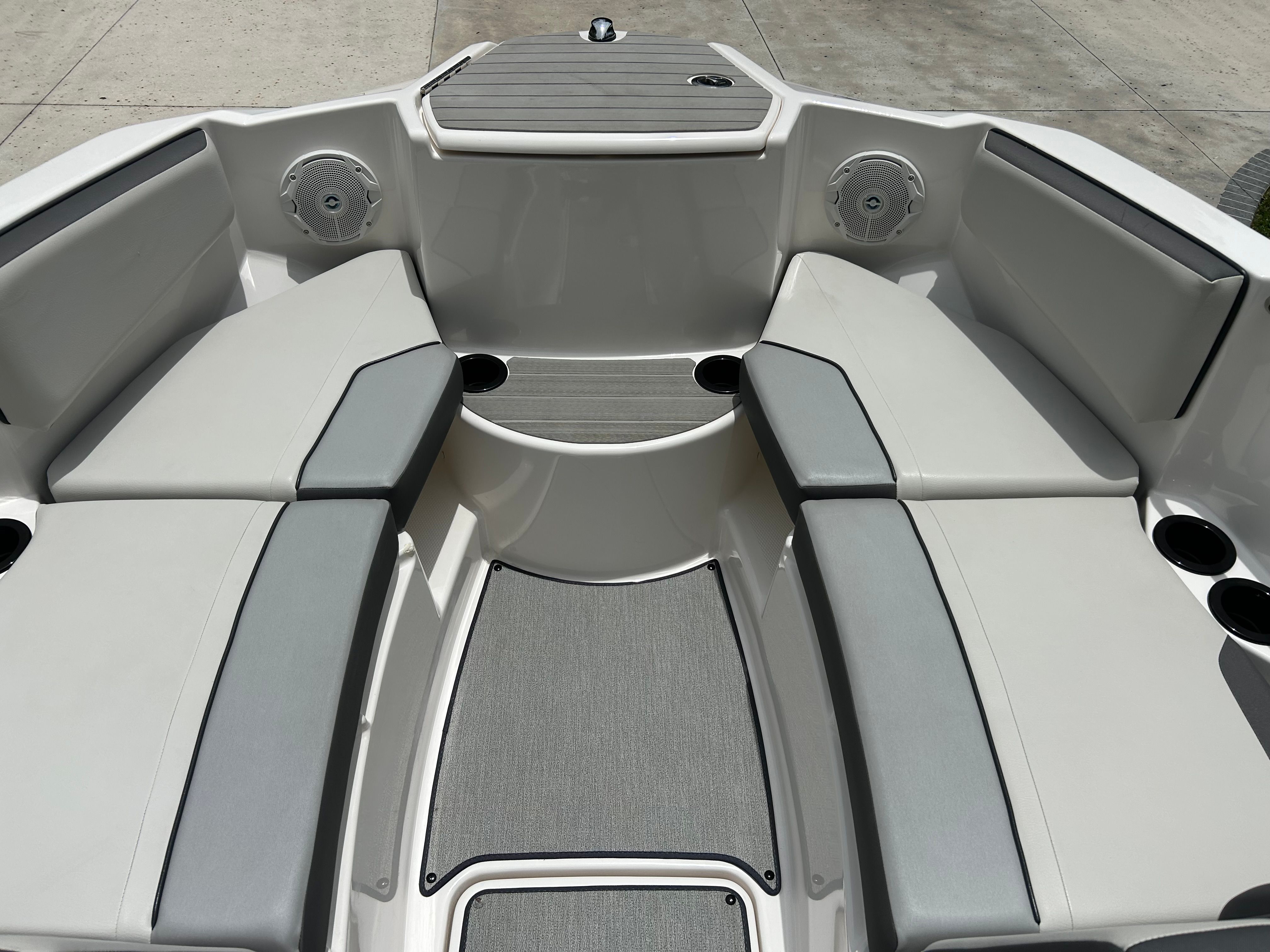 The image shows the bow area of a modern boat with gray and white seating.