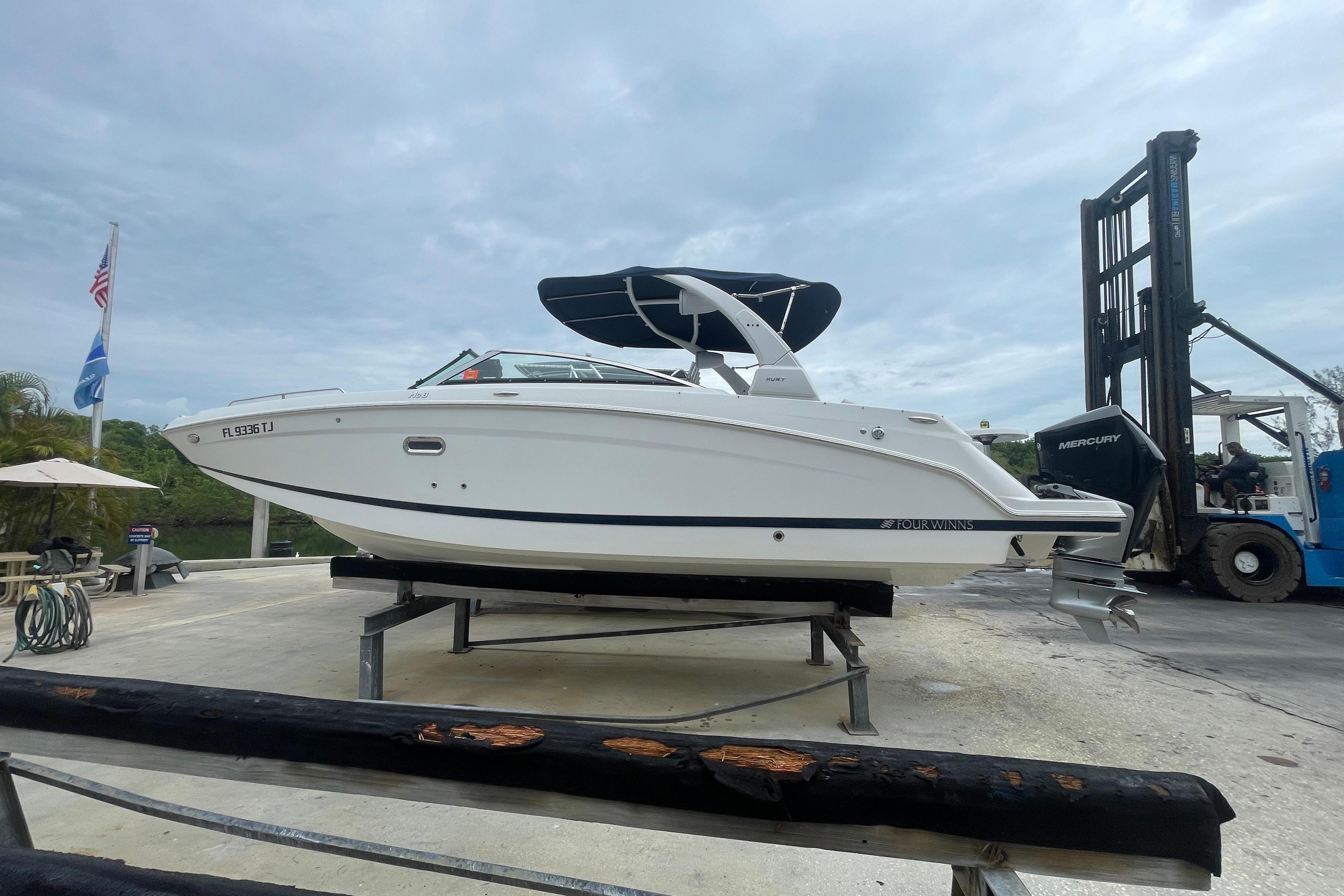 2022 Four Winns HD8 OB boat on a lift, with a cloudy sky backdrop.