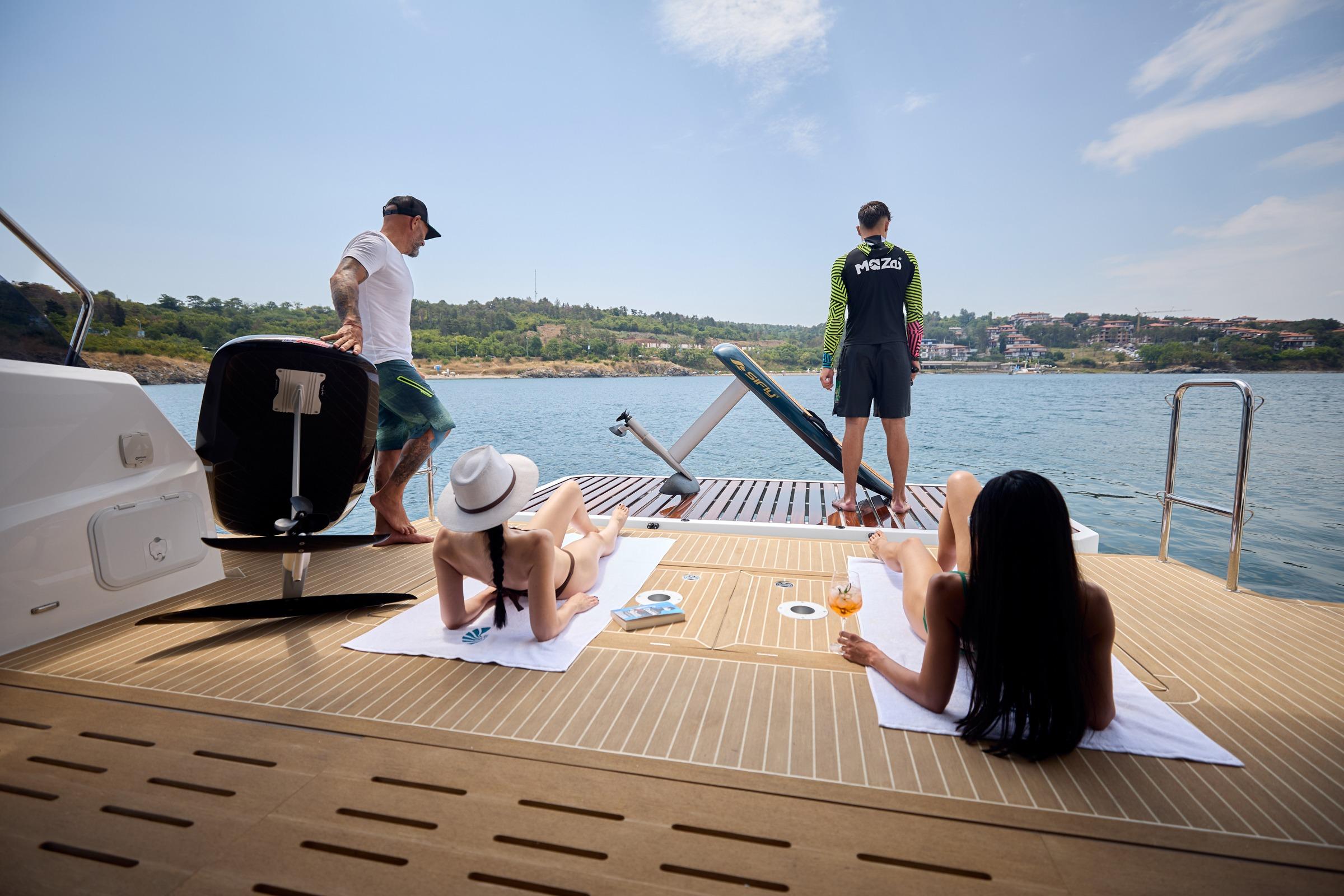 People relaxing on the deck of a 2025 Omaya 50 Power Catamaran, enjoying the sunny day.
