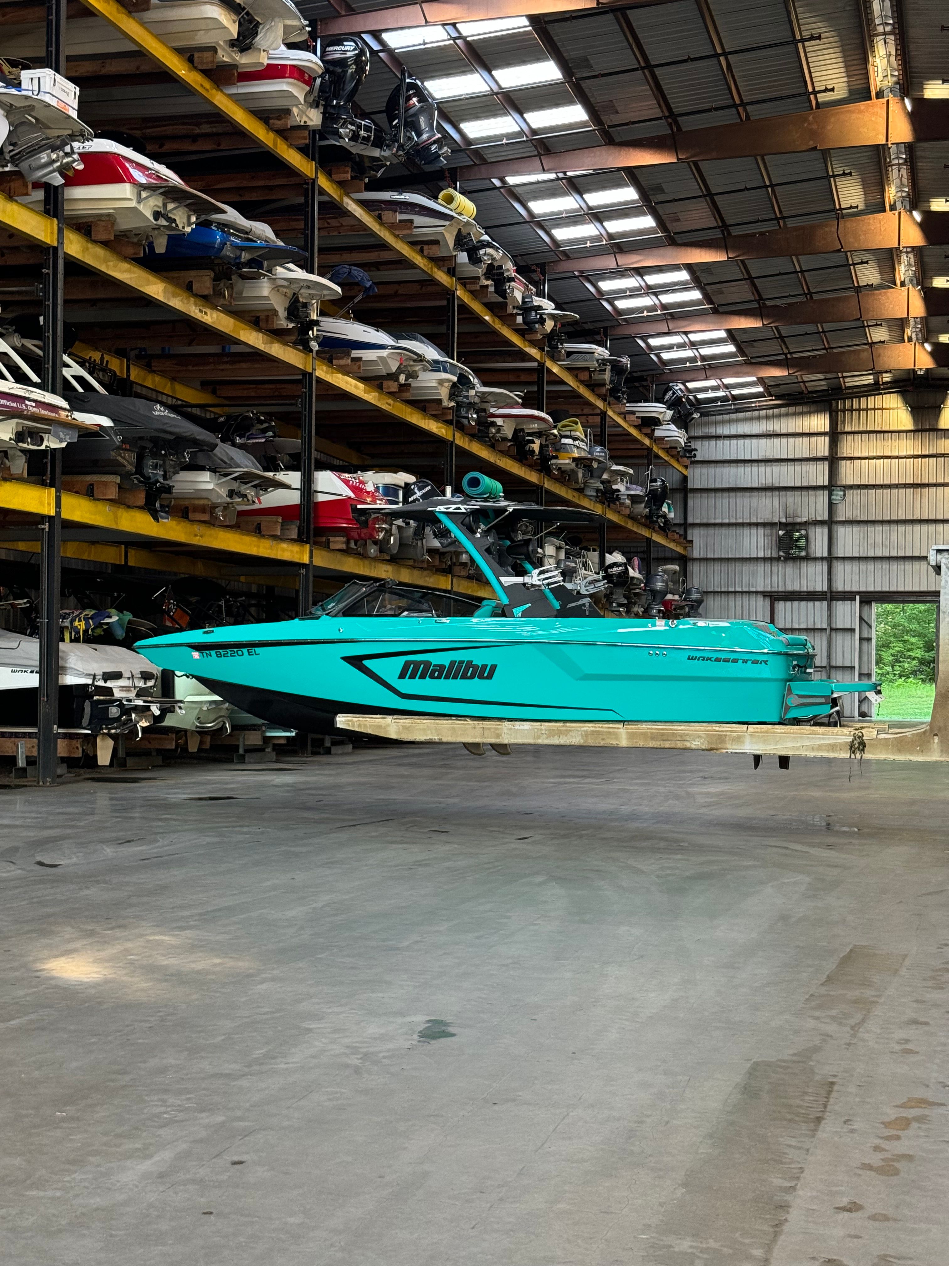 A turquoise 2023 Malibu Wakesetter 24 MXZ in a warehouse.