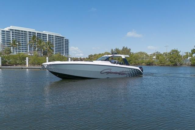 2025 Cigarette 42' Auroris boat cruising on a calm waterway with buildings in the background.