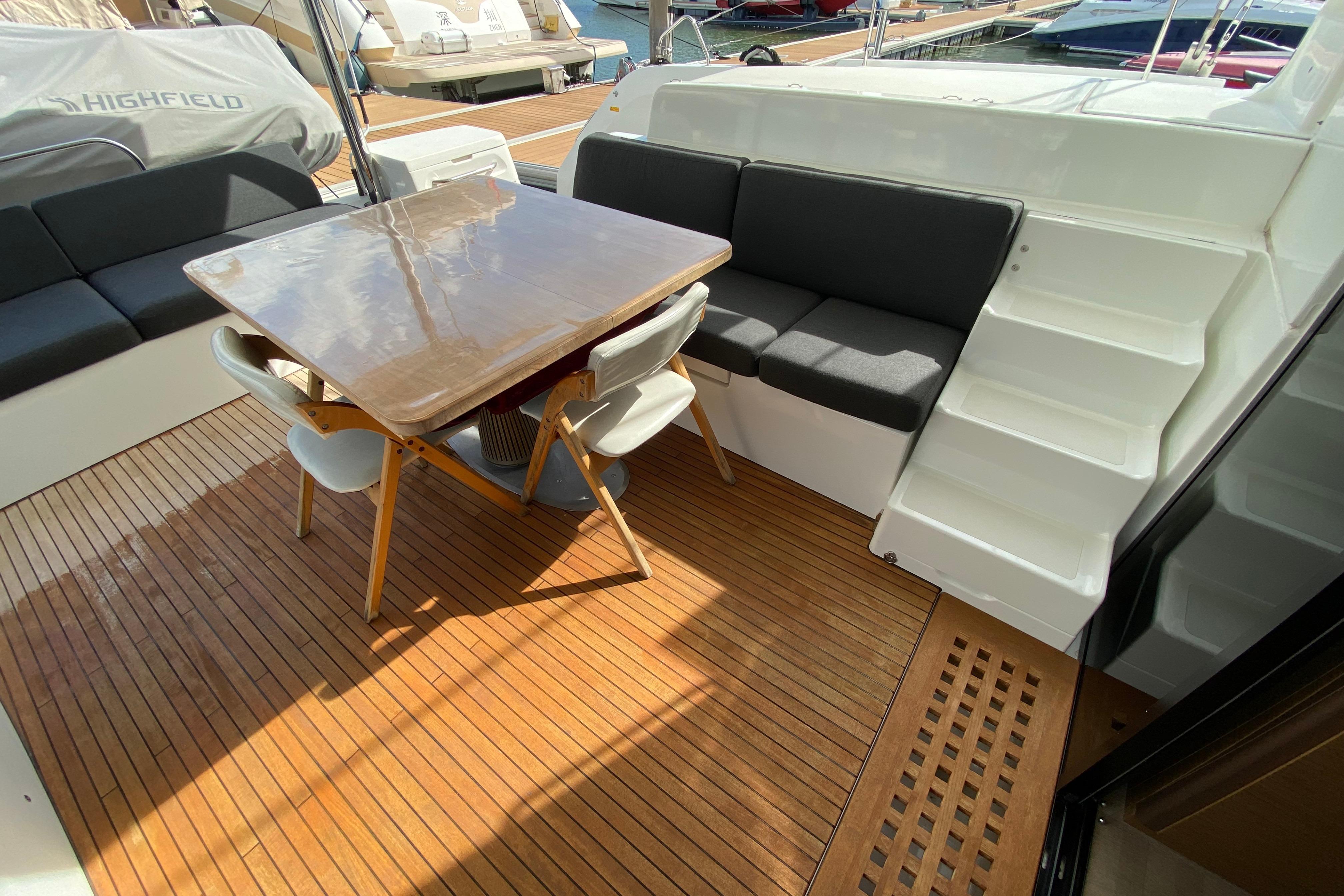 Outdoor seating area on 2022 Lagoon 50 yacht with wooden deck and modern furniture.