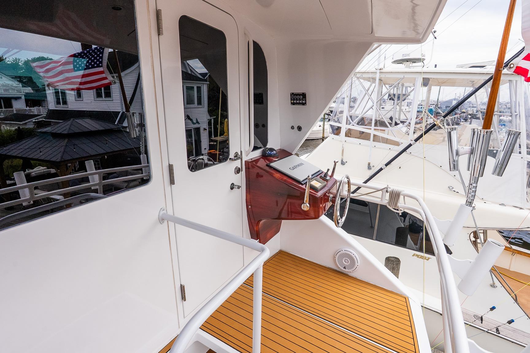 2002 Viking 61 Enclosed Bridge yacht helm with wooden deck and marina view.