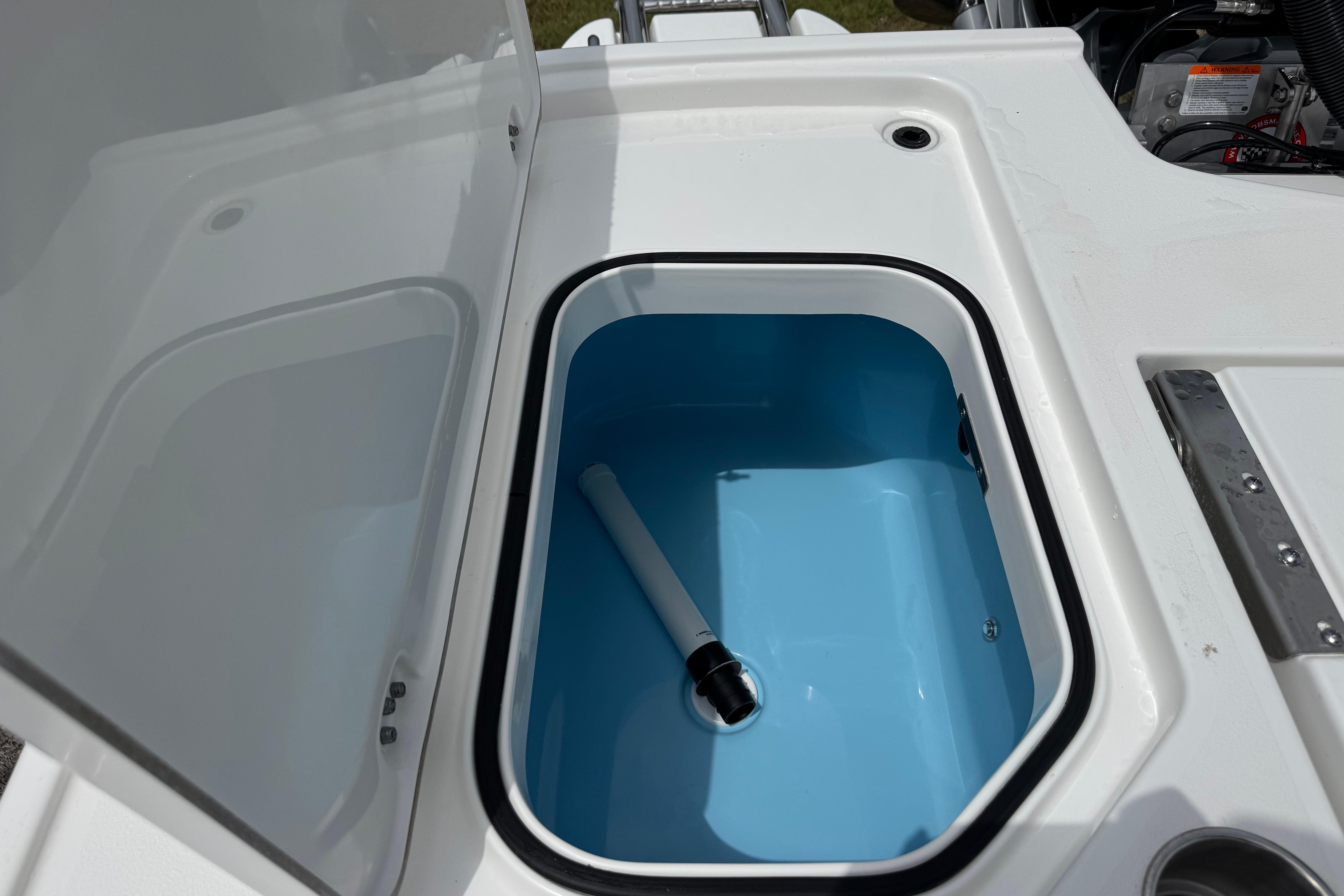 Open storage compartment on 2027 Caymas 26 HB boat, featuring a blue interior.