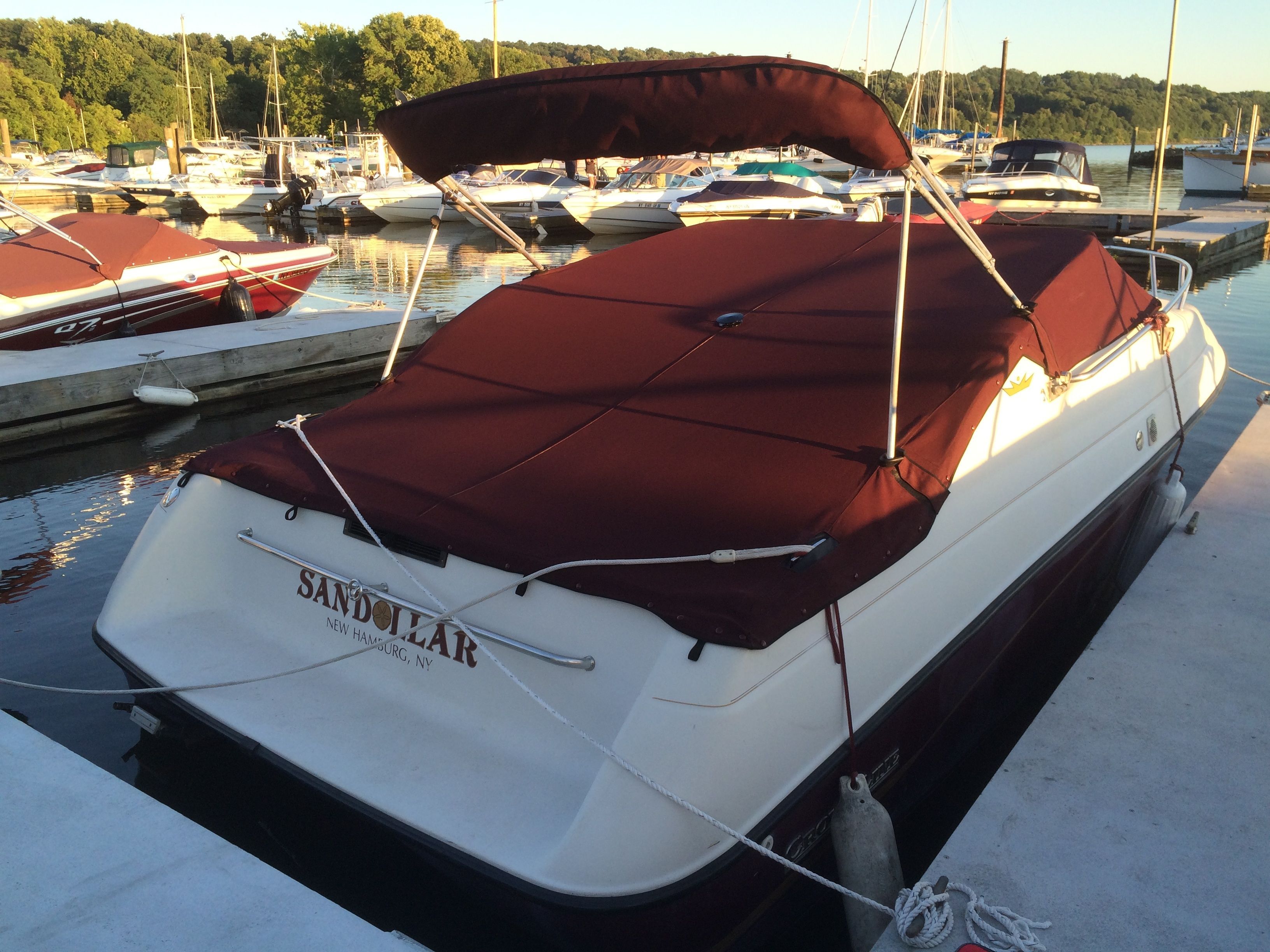 A 1992 Crownline Cudy Cruiser with a red canopy docked at a marina.