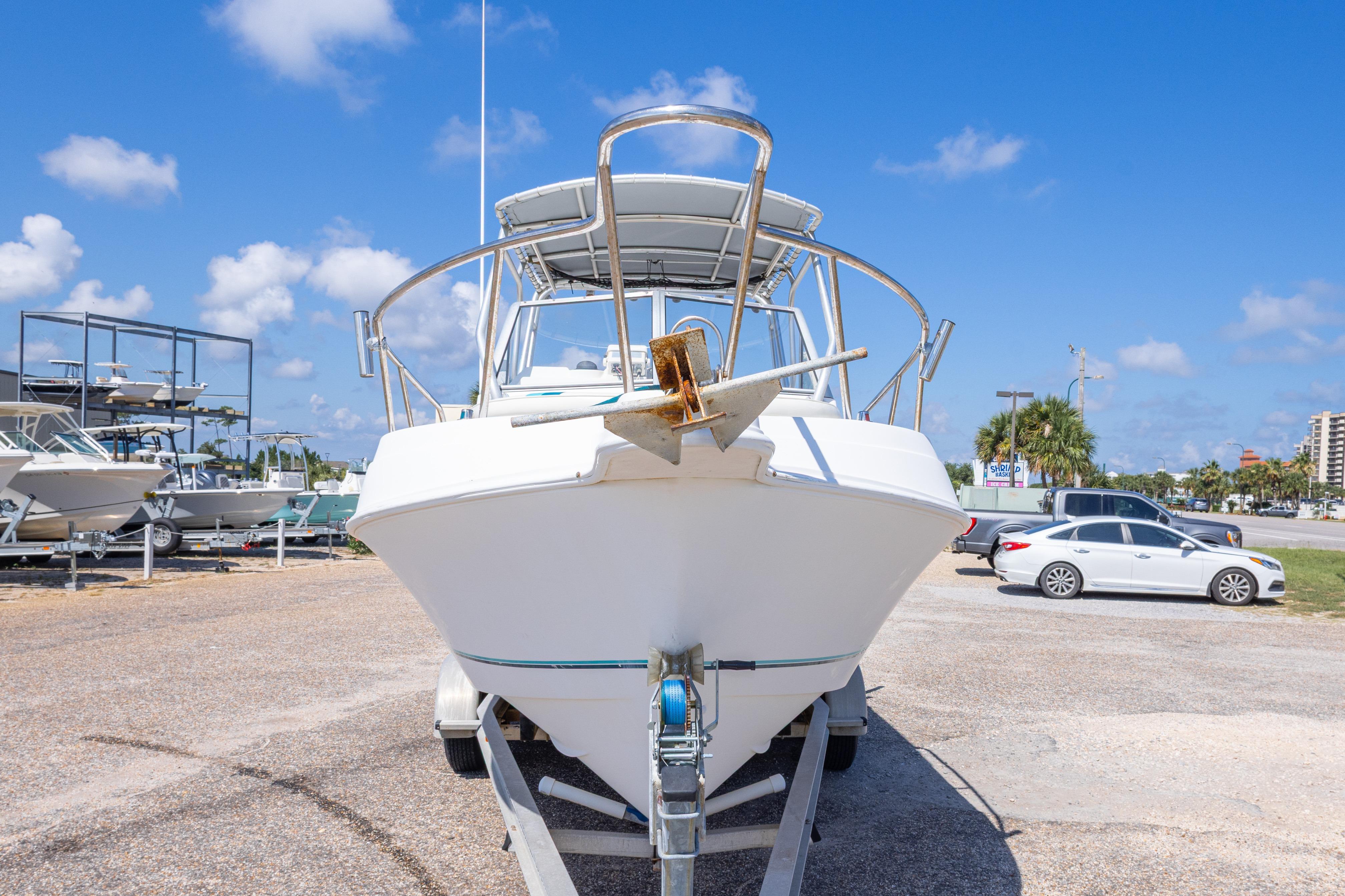 1999 Aquasport 225 Explorer boat on trailer under clear blue sky.