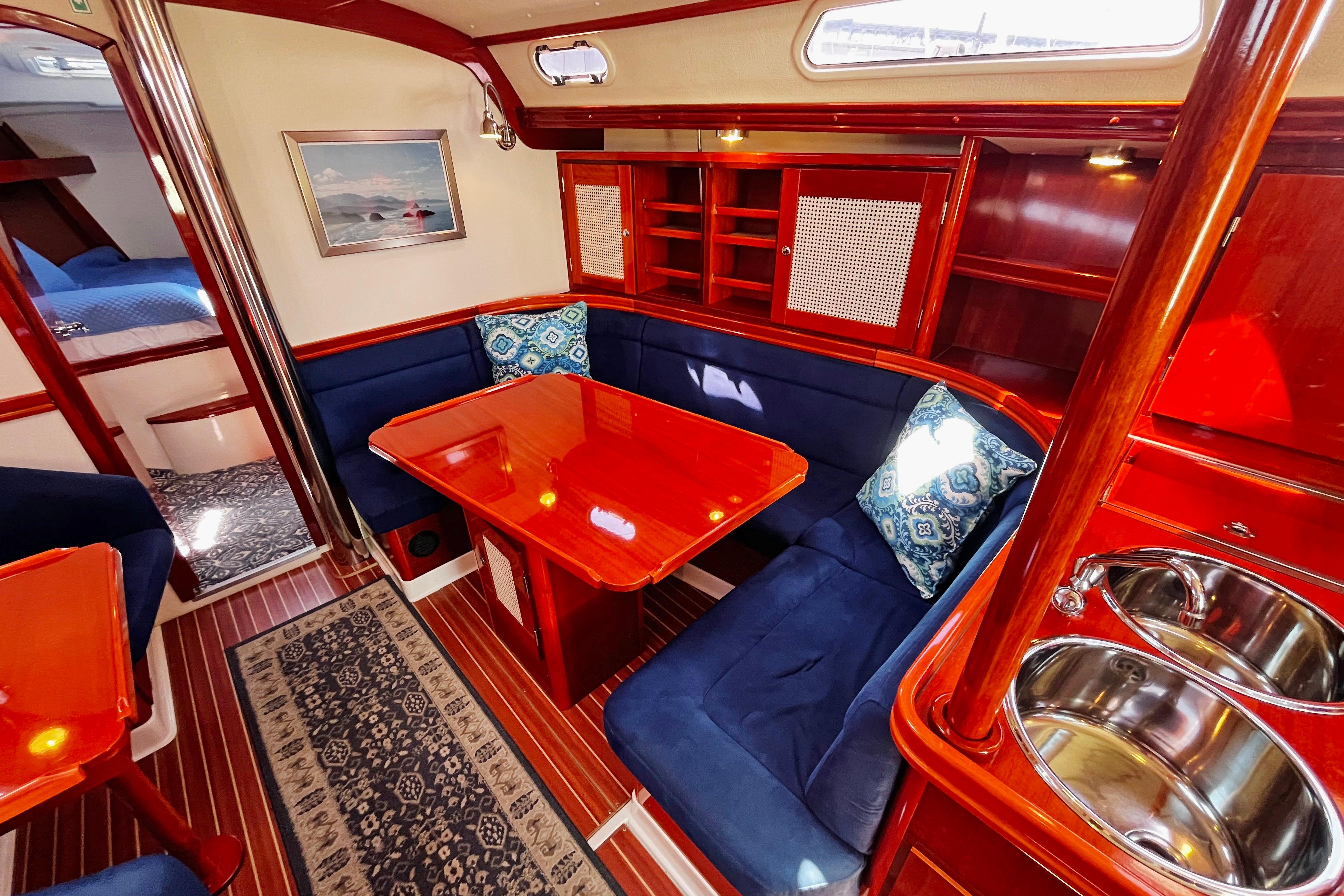 Luxurious 2004 Hanse 411 yacht interior with polished wood, blue seating, and elegant dining area.