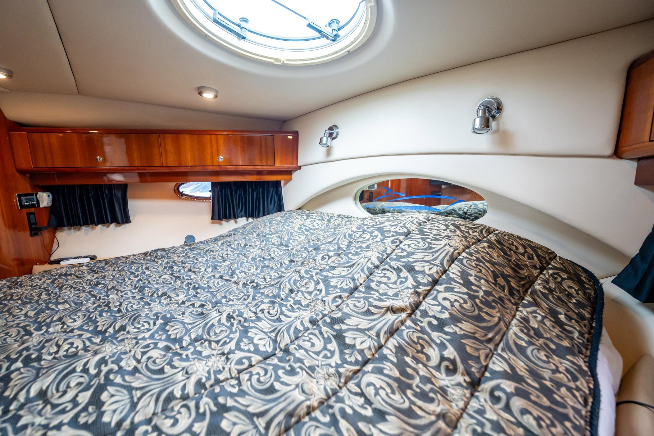 Luxurious cabin interior of 2008 Regal Commodore 4460 yacht with elegant bedding and wood accents.