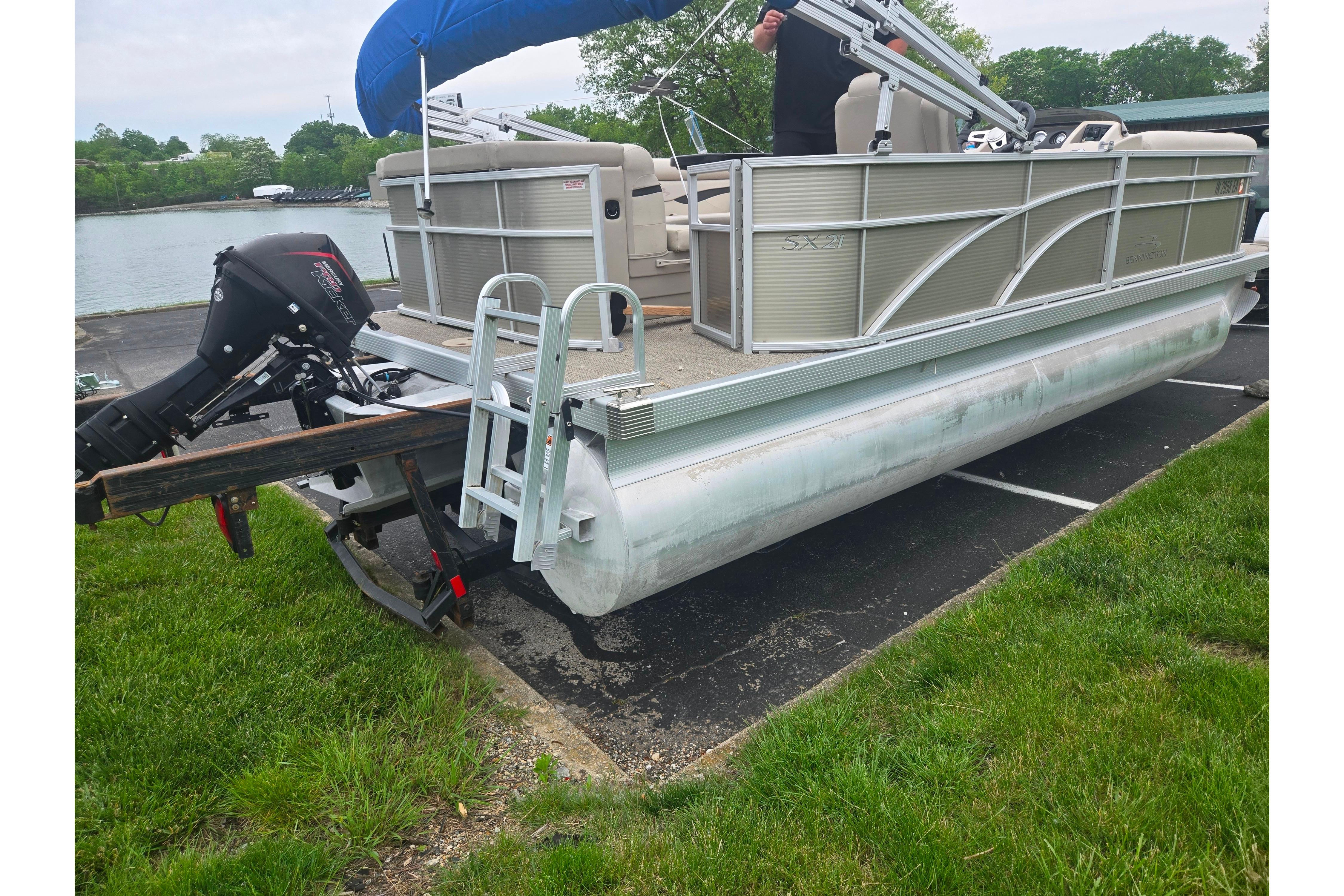 2018 Bennington 21 SLX pontoon boat with outboard motor, docked near a grassy area.