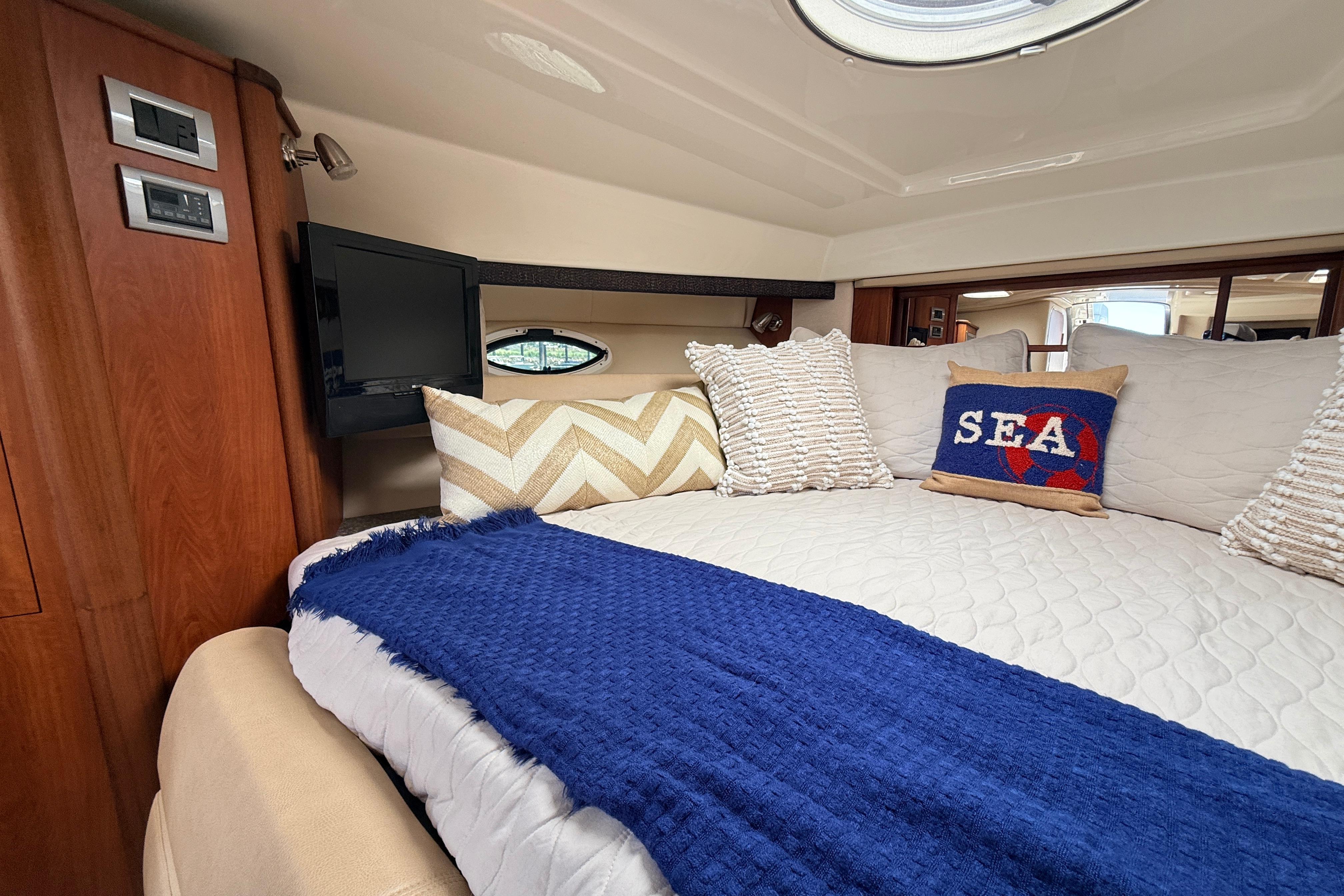 Luxurious interior of 2011 Monterey 320 Sport Yacht with cozy bedding and nautical decor.