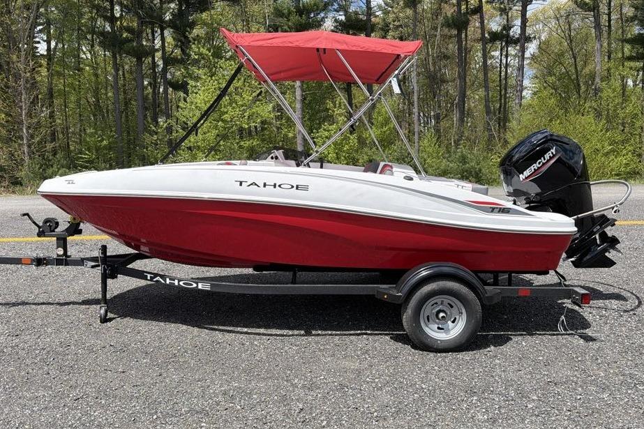 2026 Tahoe T16 boat with red hull and canopy on a trailer, parked outdoors.