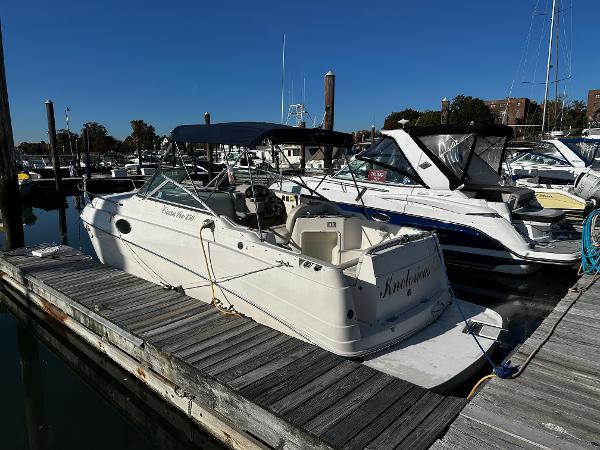 2004 Rinker Fiesta Vee 250 boat docked at marina under clear blue sky.
