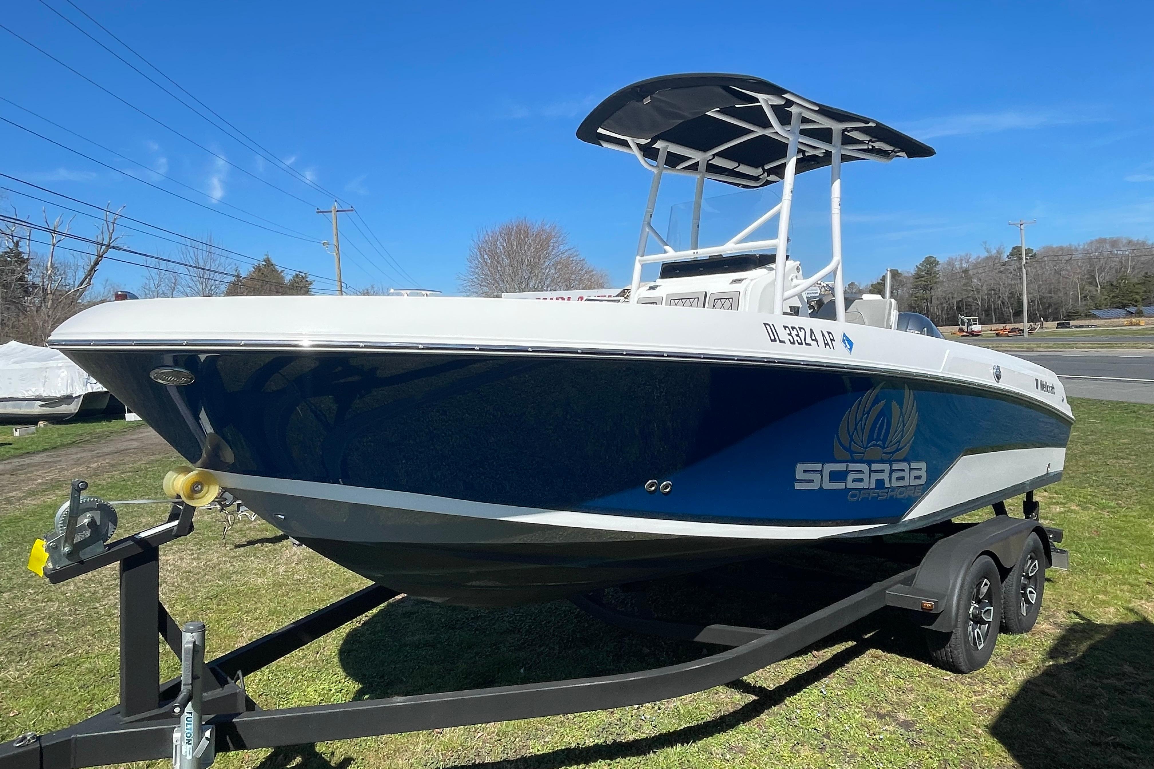 2022 Wellcraft 202 Fisherman boat on trailer, blue and white design, parked on grass.
