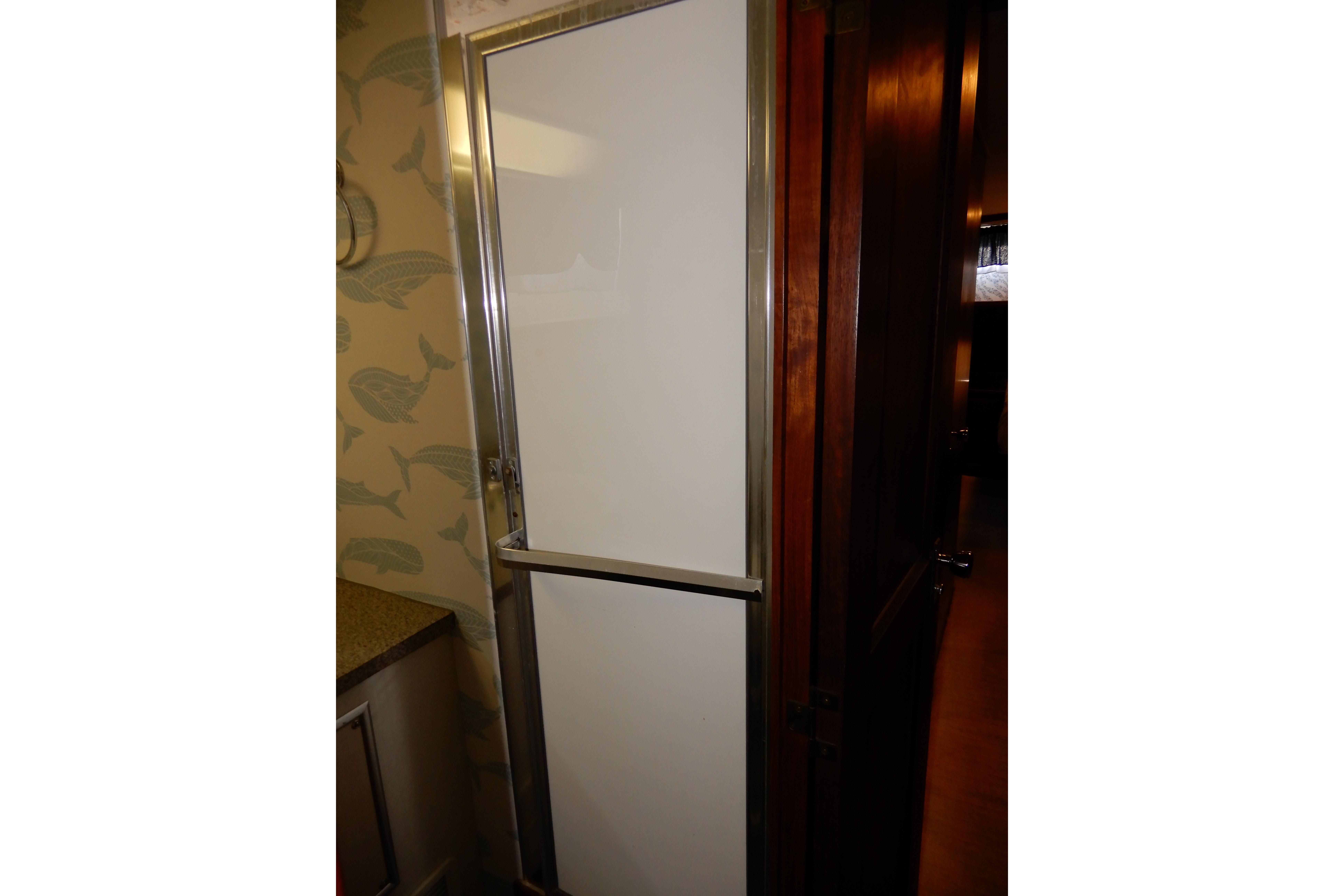 Shower door inside 1974 Hatteras 53 Motor Yacht with fish-patterned wallpaper.