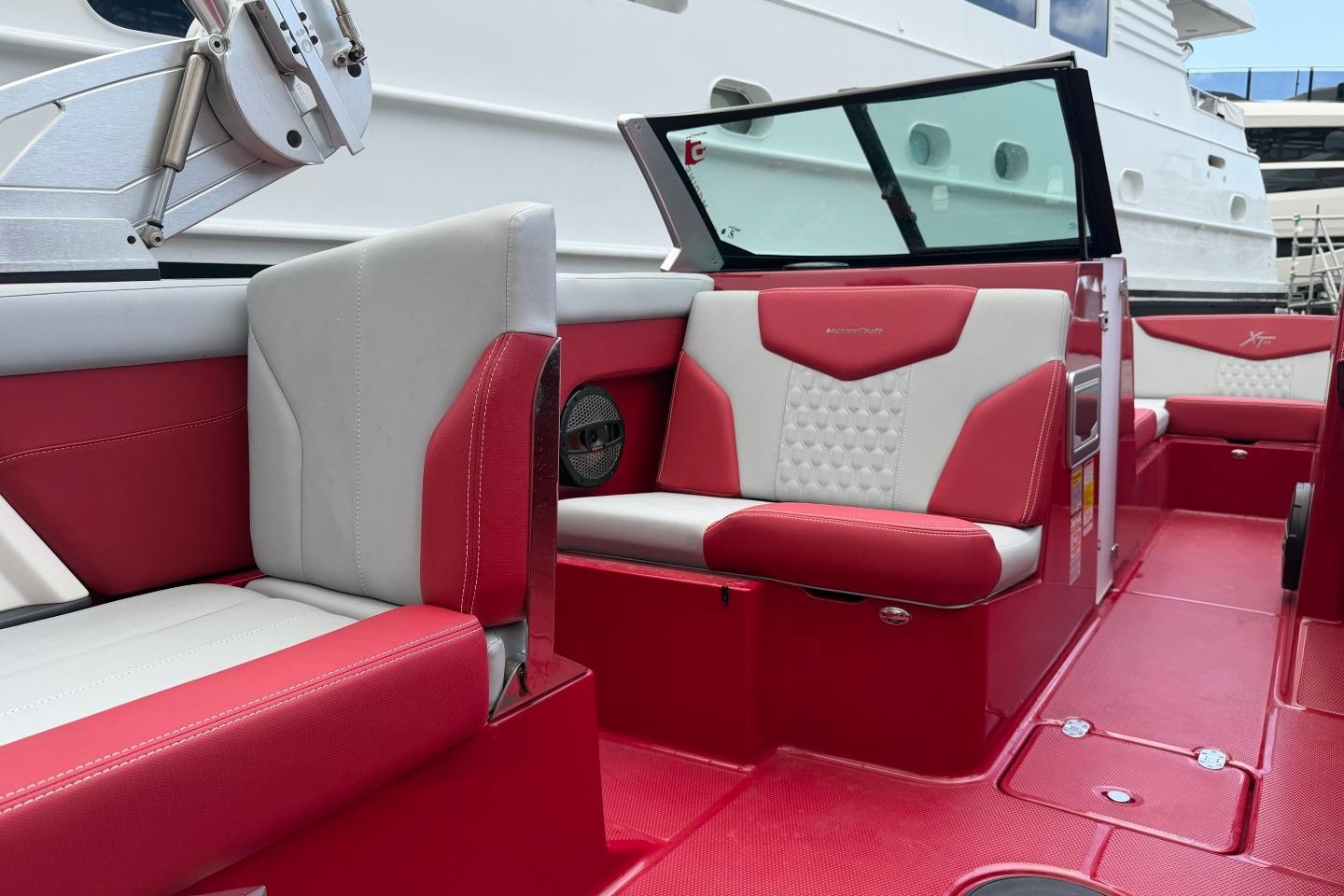 2023 MasterCraft X24 boat interior with red and white seating, docked near a yacht.
