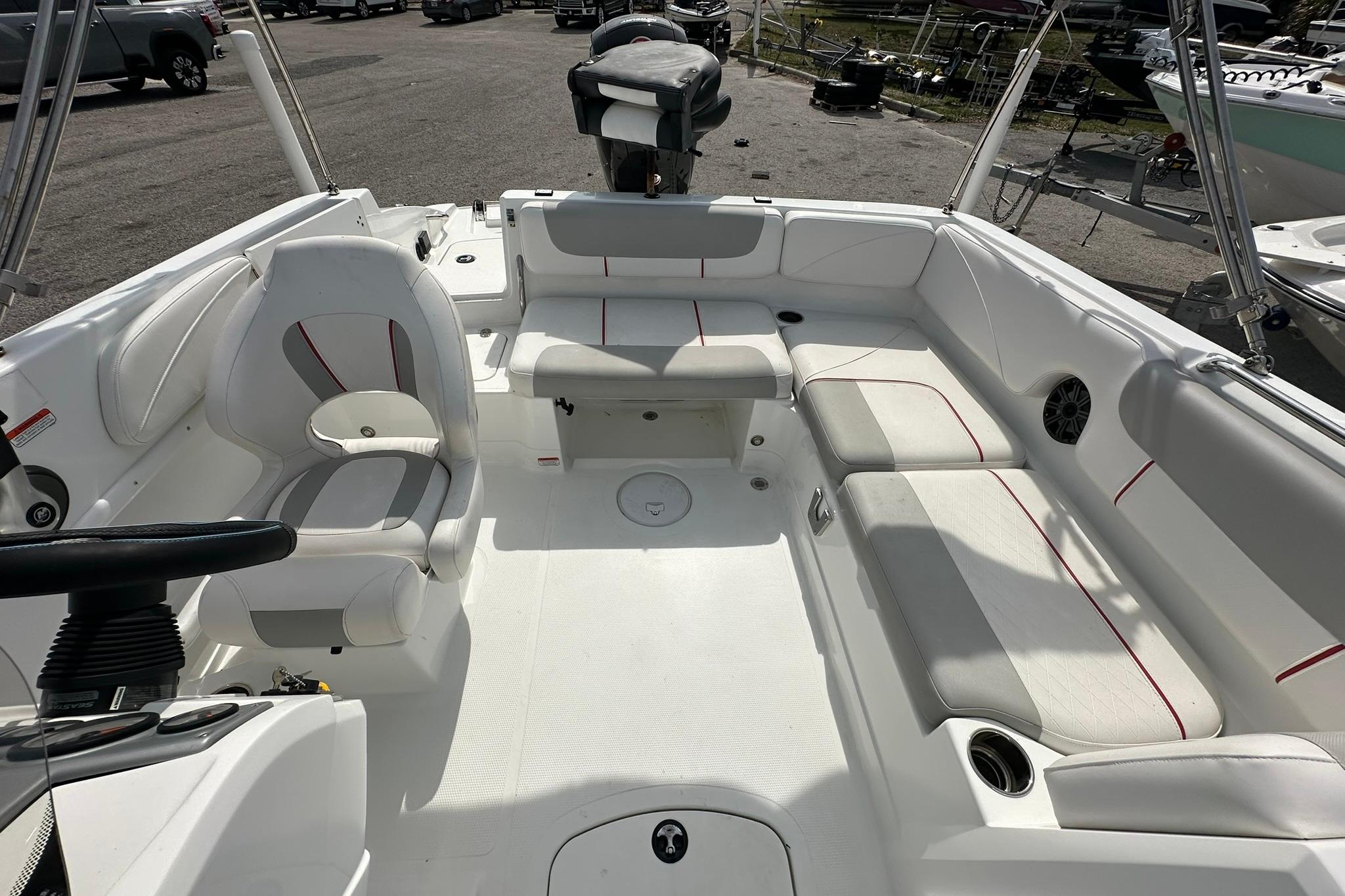 2021 Tahoe 2150 boat interior with white seating and red accents, parked outdoors.