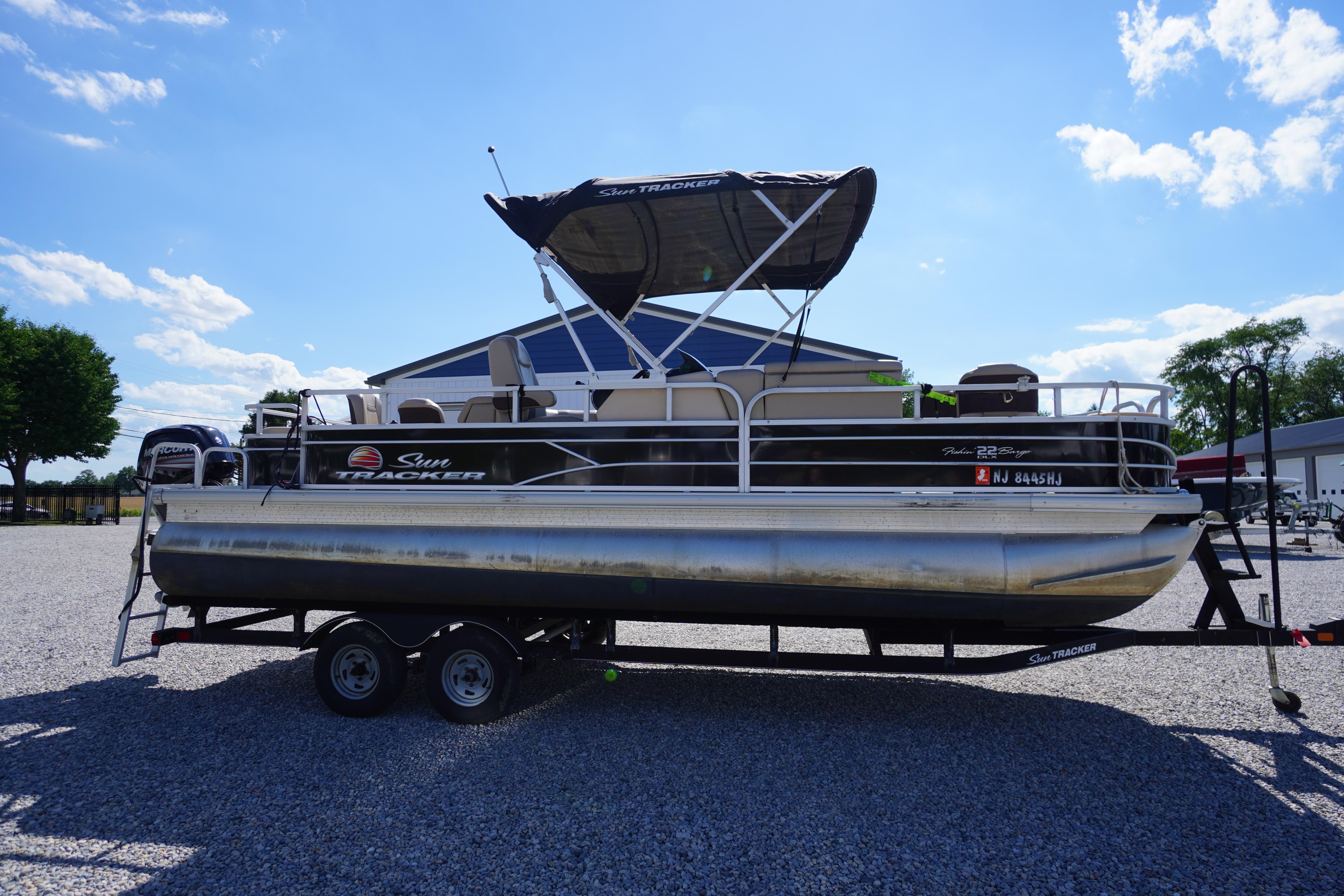 2019 SUNTRACKER Fishin' Barge 22 DLX pontoon boat on trailer under clear sky.