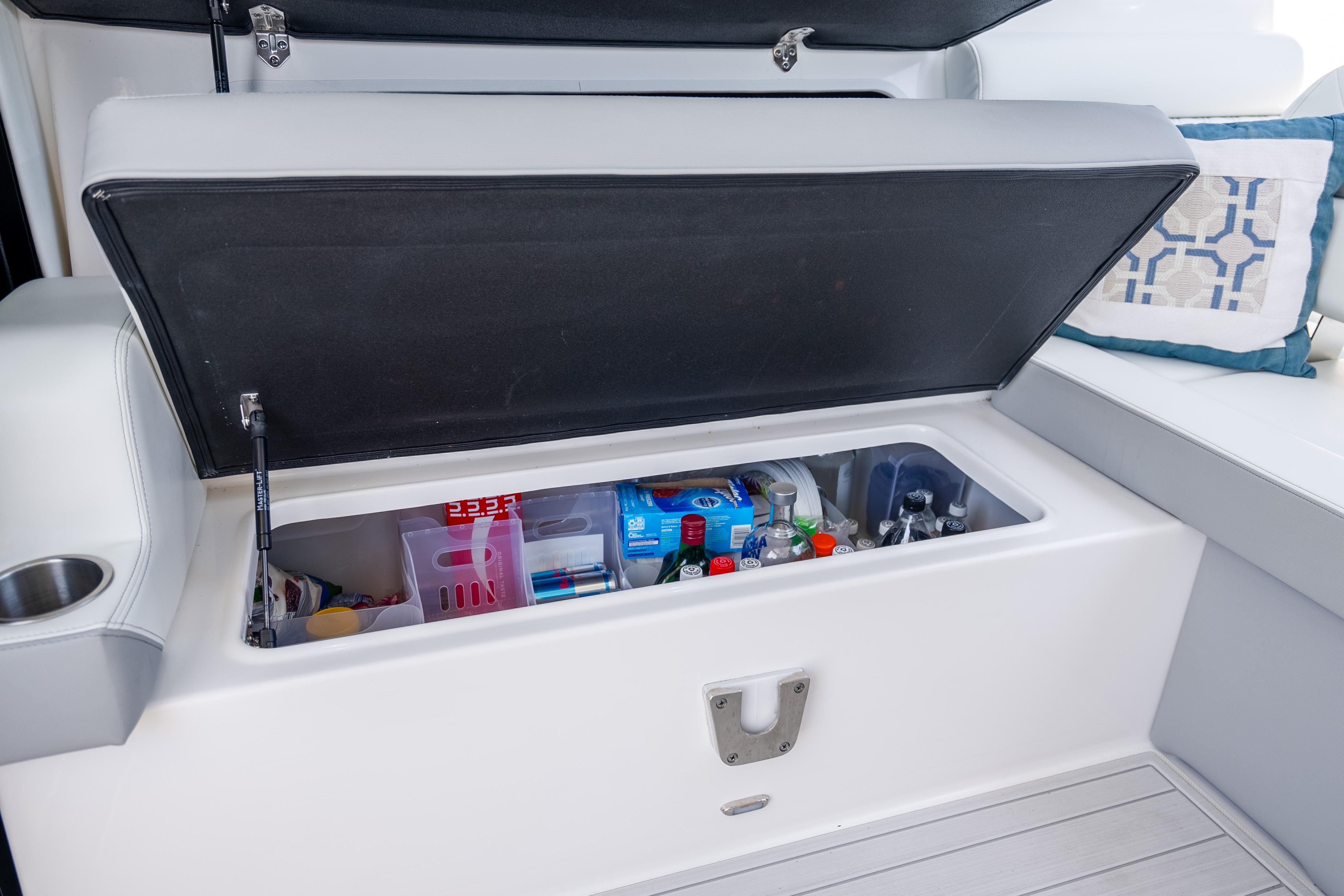 Open storage compartment on 2022 Regal 36 Grande Coupe, stocked with beverages and snacks.