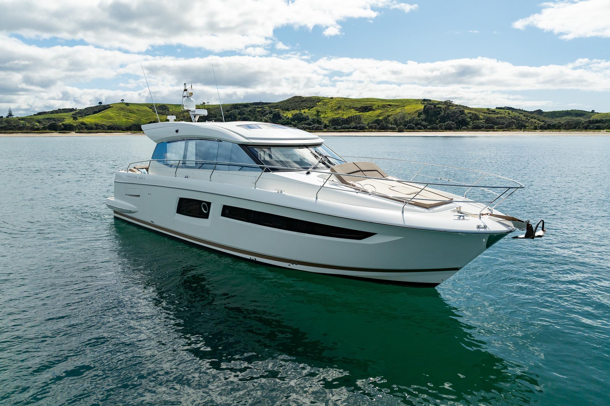 Luxurious 2014 Prestige 500 S yacht cruising on serene waters near a lush coastline.