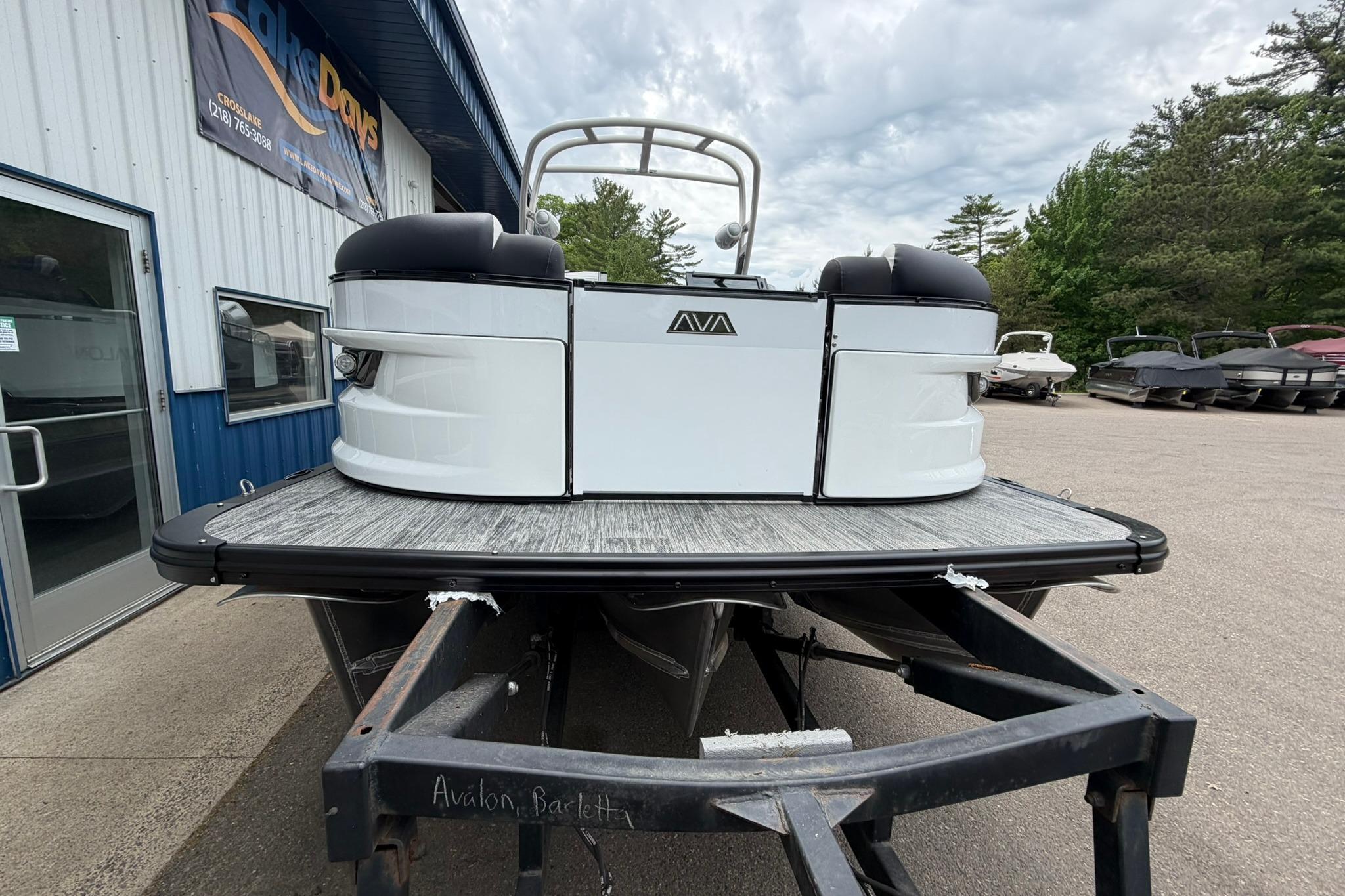 2026 Avalon Excalibur LTD Flex Lounge boat on trailer, parked outside dealership.