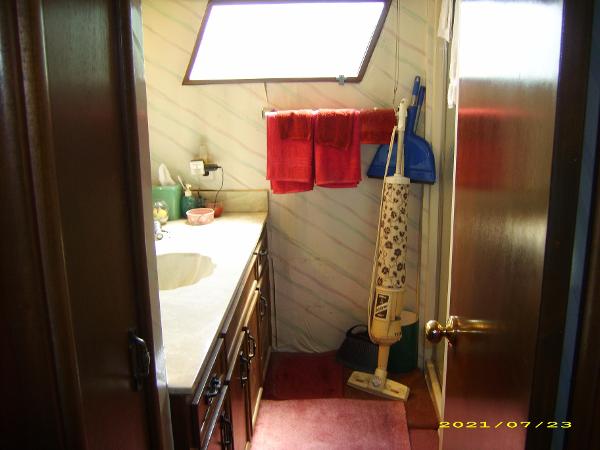 1980 Pluckebaum Baymaster bathroom with sink, red towels, and vintage vacuum cleaner.