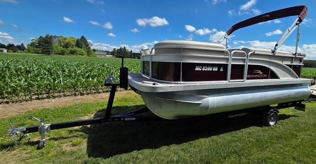 A 2018 Bennington 18SL pontoon boat on a trailer beside a cornfield.