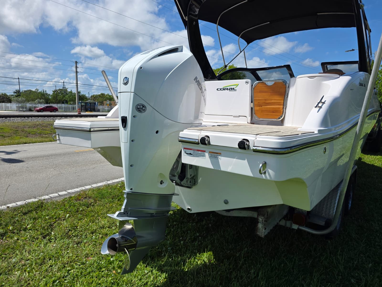 The image shows a white boat with an outboard motor, positioned on grass.