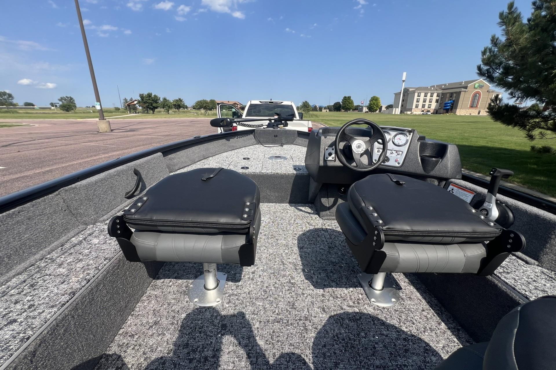 2026 Tracker Pro Guide V-16 SC boat interior with seating and steering console, parked outdoors.