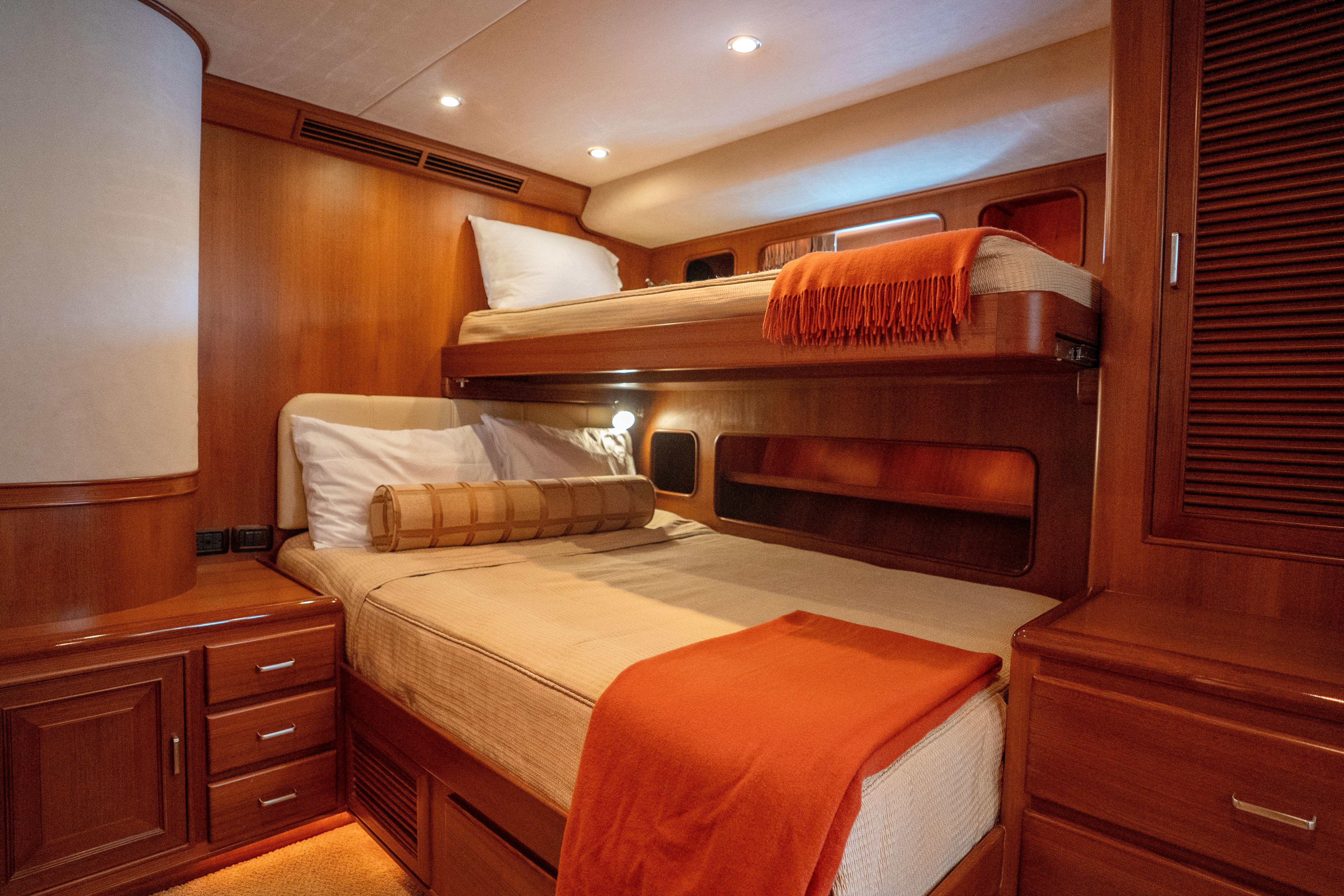 Luxurious cabin interior of 2006 Fleming 75 yacht with wooden furnishings and cozy bedding.