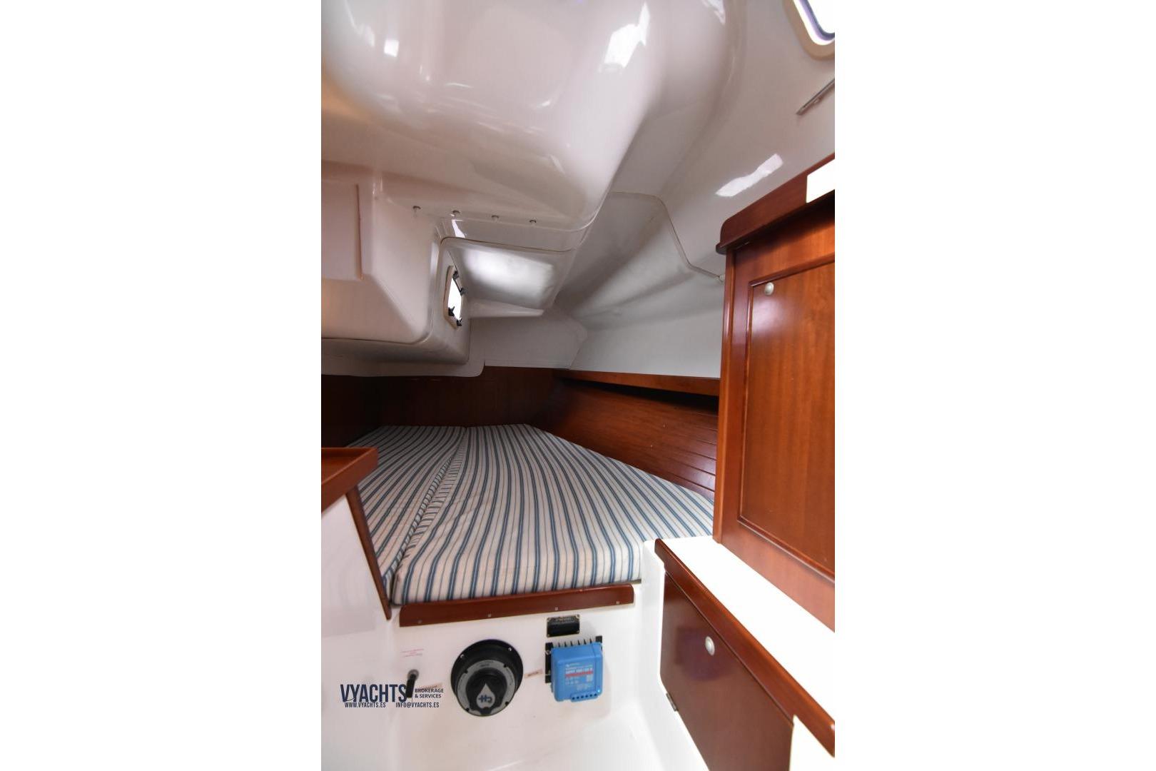 Interior cabin of 2000 Ronautica RO 300 yacht with striped bedding and wooden cabinetry.