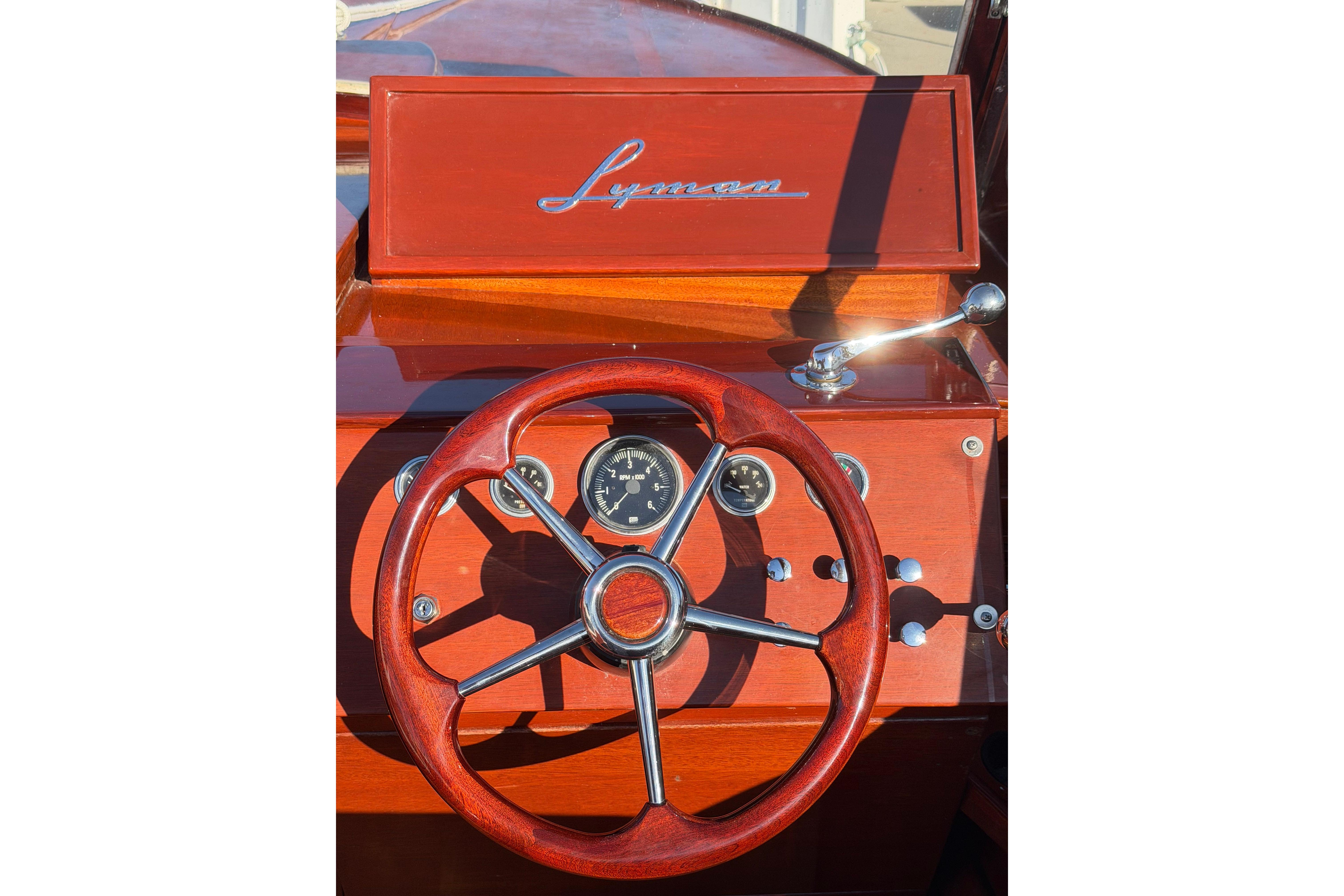 1964 Lyman 25 Sleeper boat dashboard with wooden steering wheel and vintage controls.