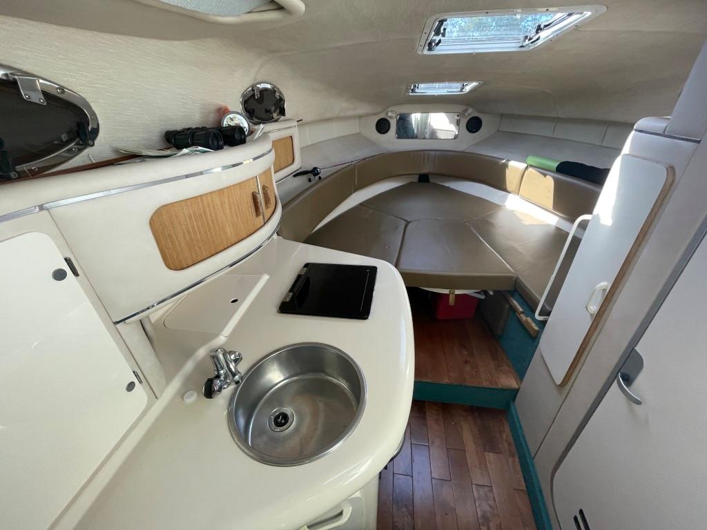 Interior of a 1995 Sea Ray 270 Sundancer boat, featuring a compact kitchen and cozy sleeping area.