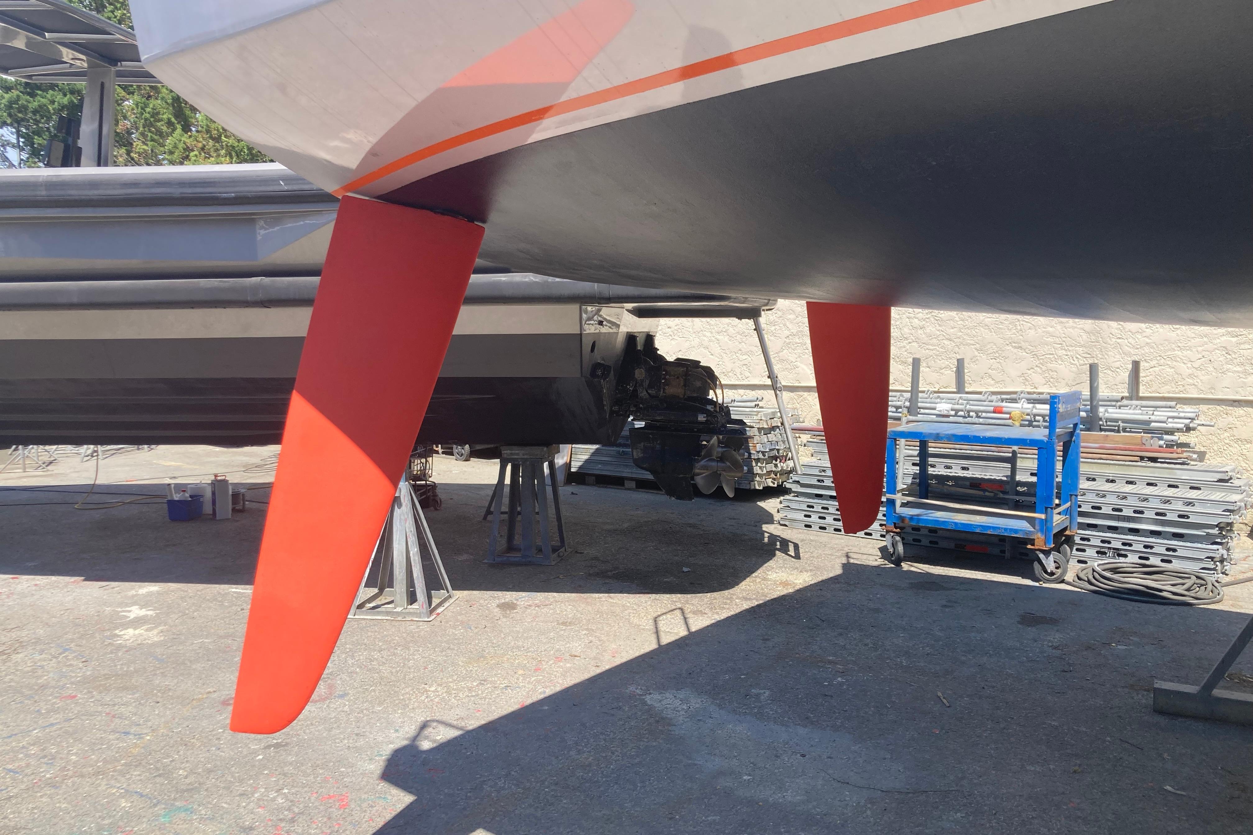 Red keel of Black Pepper CODE 1 yacht, 2014 model, in a shipyard setting.