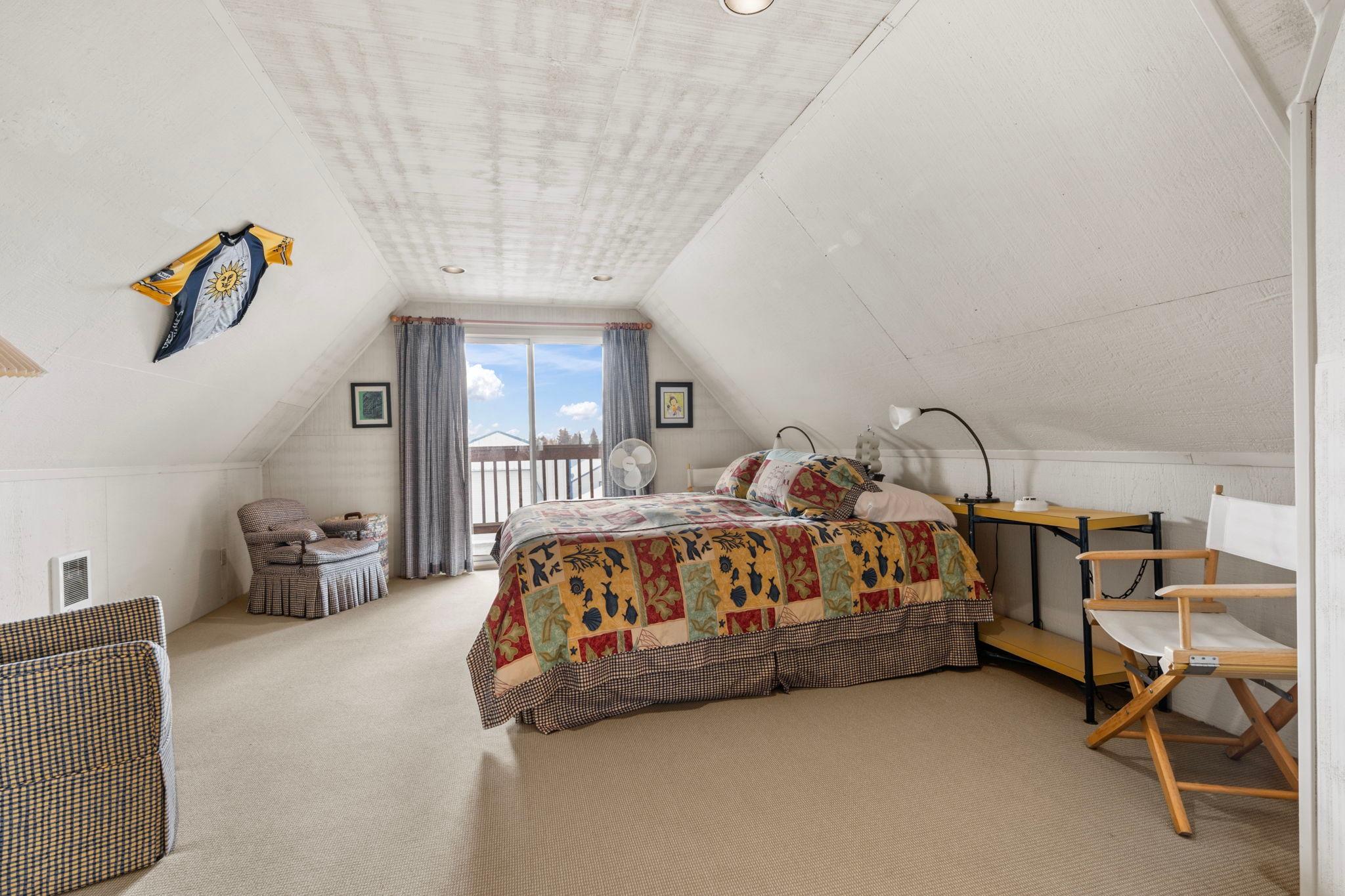 Cozy attic bedroom with colorful quilt, vintage decor, and balcony view in 1976 custom boathouse.