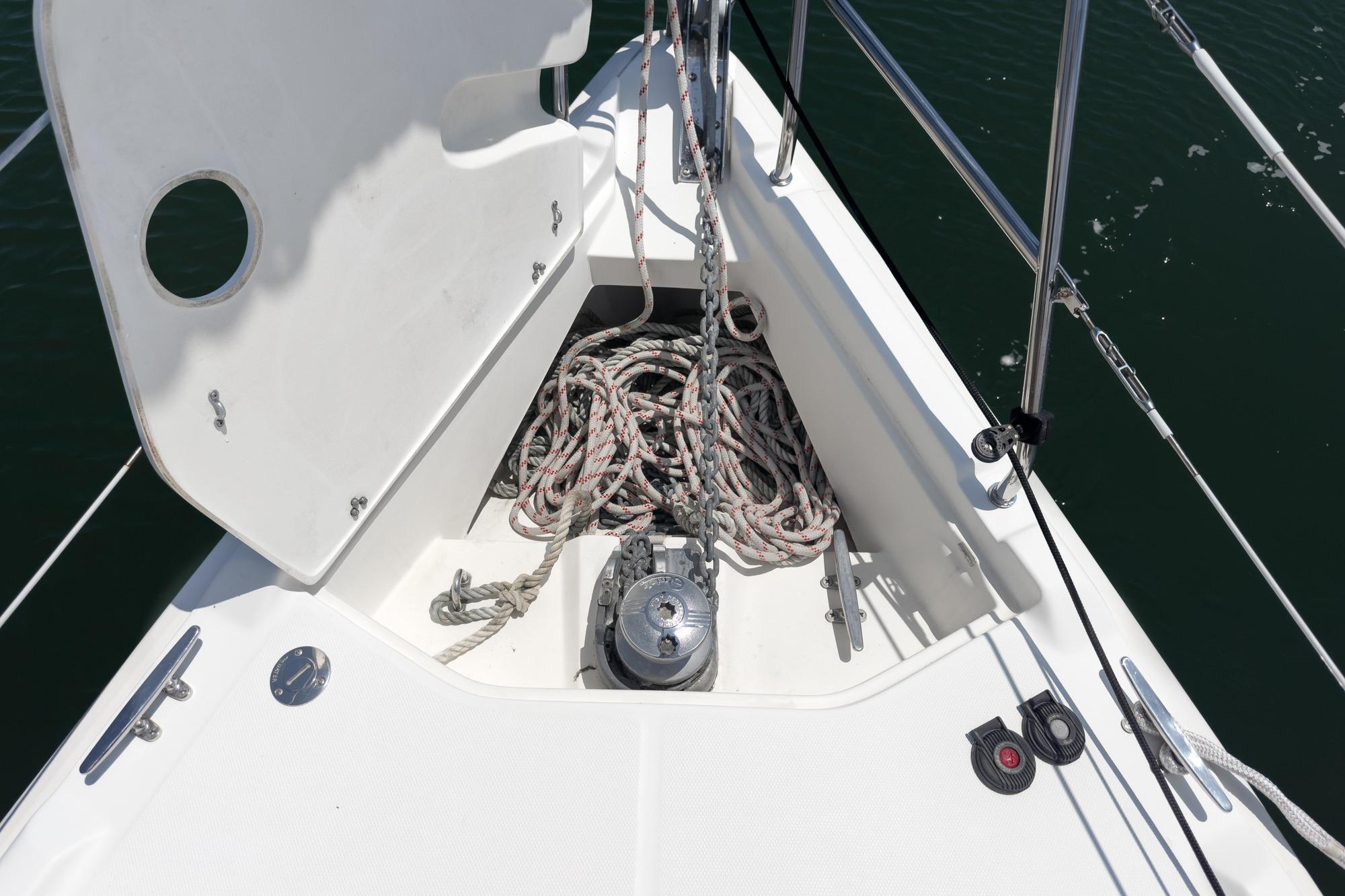 Anchor locker of a 2015 Hunter 33 sailboat with coiled ropes and winch.